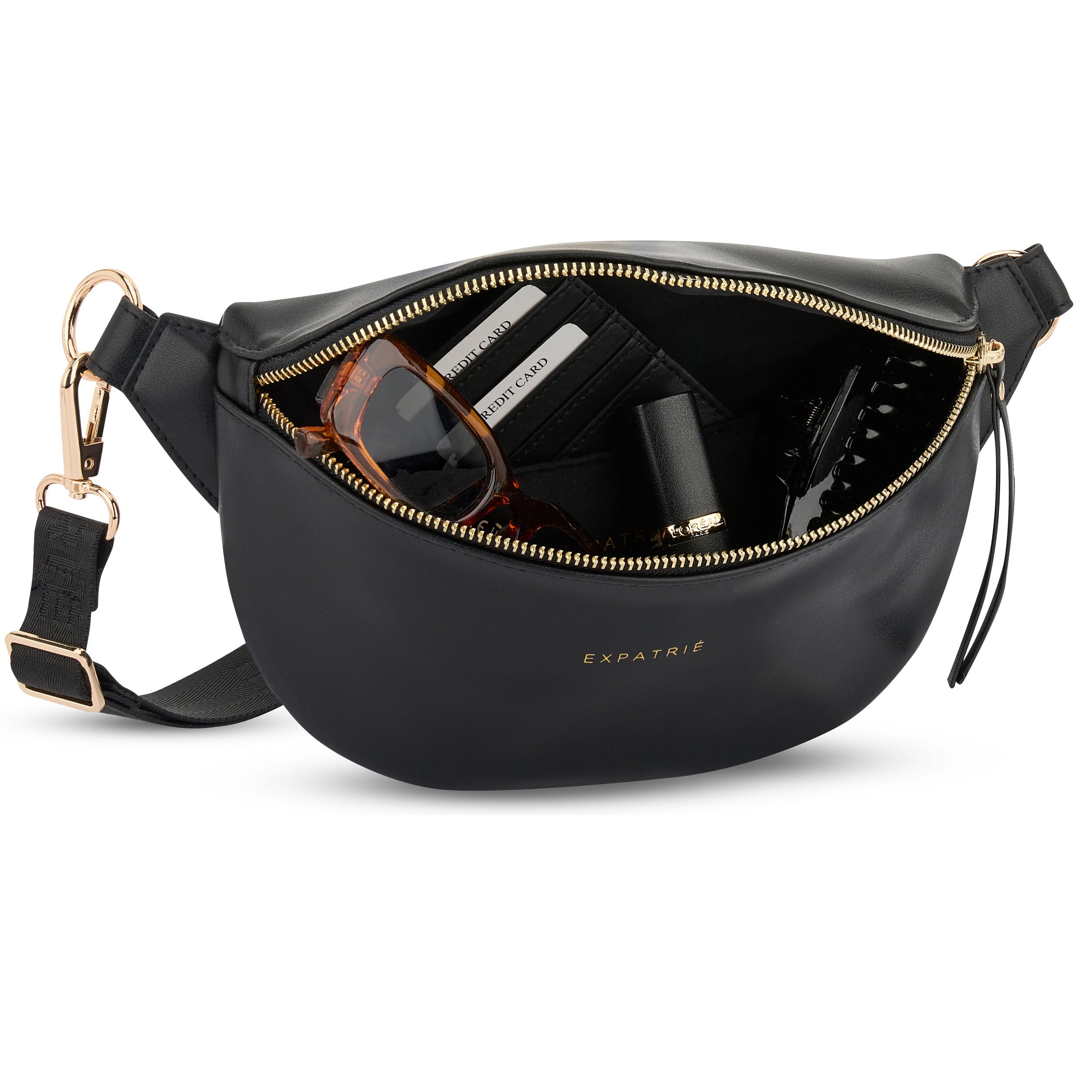 Schwarze Bauchtasche Alice Small von Expatrié mit goldfarbenem Reißverschluss und verstellbarem Gurt, geöffnet mit Sonnenbrille, Lippenstift und Kreditkarten