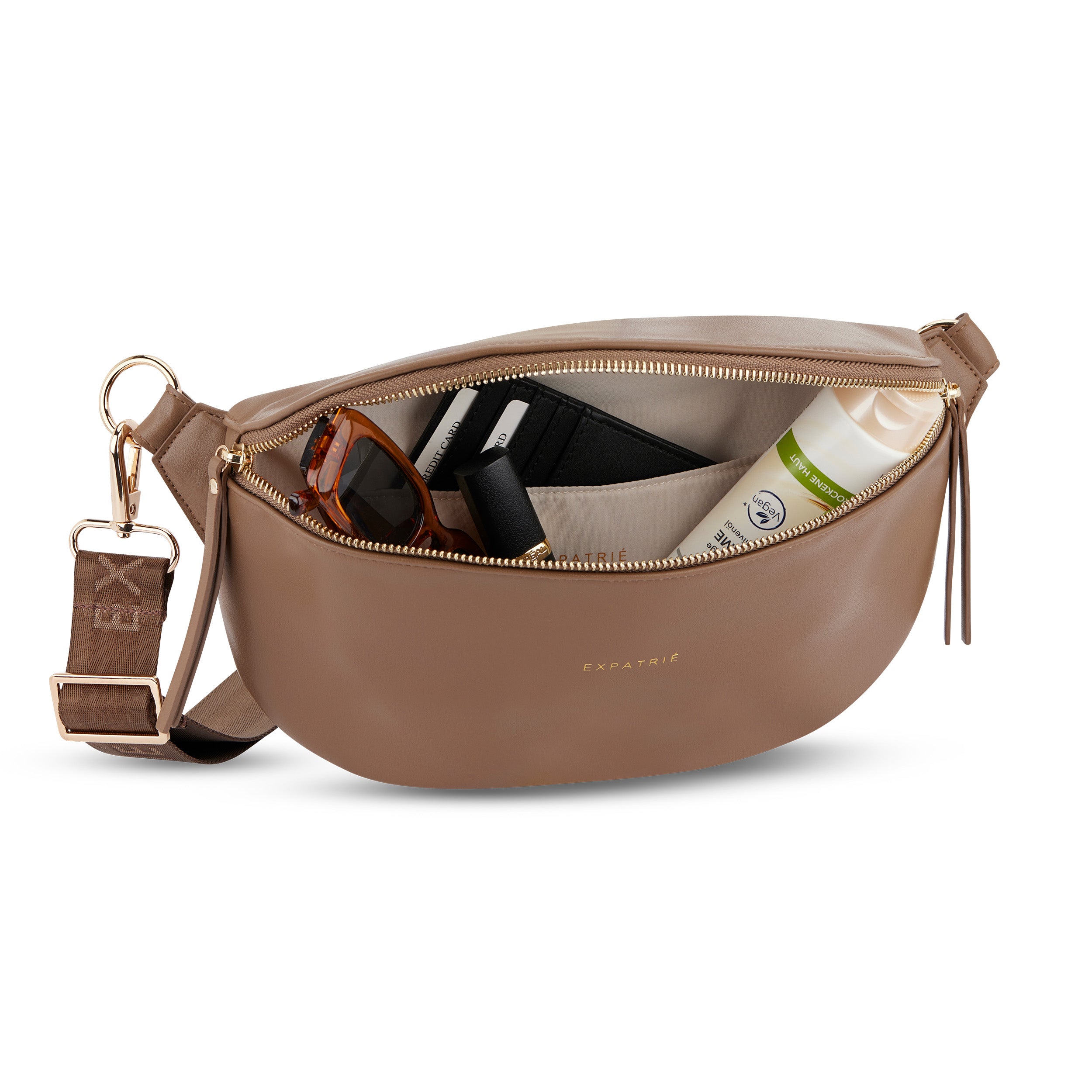 Bauchtasche Alice Medium aus braunem Leder mit goldfarbenem Reißverschluss, gefüllt mit Sonnenbrille, Lippenstift, Kartenetui und Hautpflege