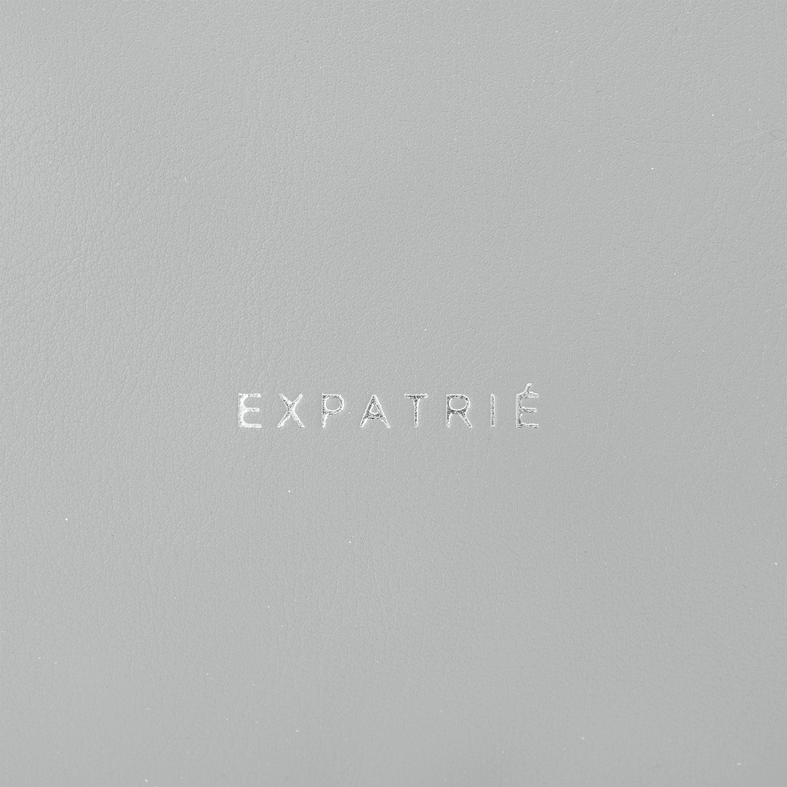 Logo 'Expatrié' geprägt auf grauem Kunstleder der Bauchtasche Justine PU
