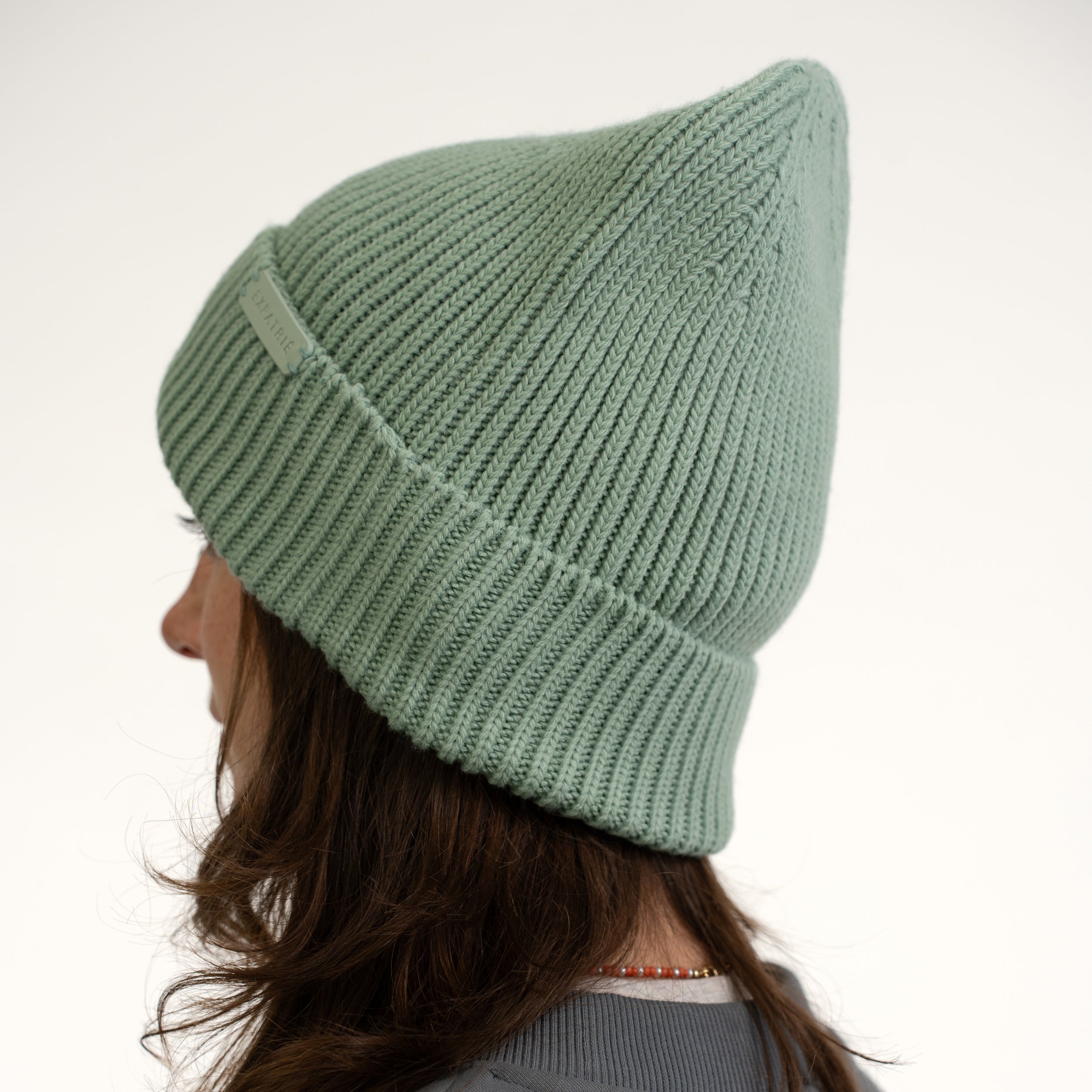 Grüne gestrickte Mütze Luna mit Umschlag an einer Frau von der Seite