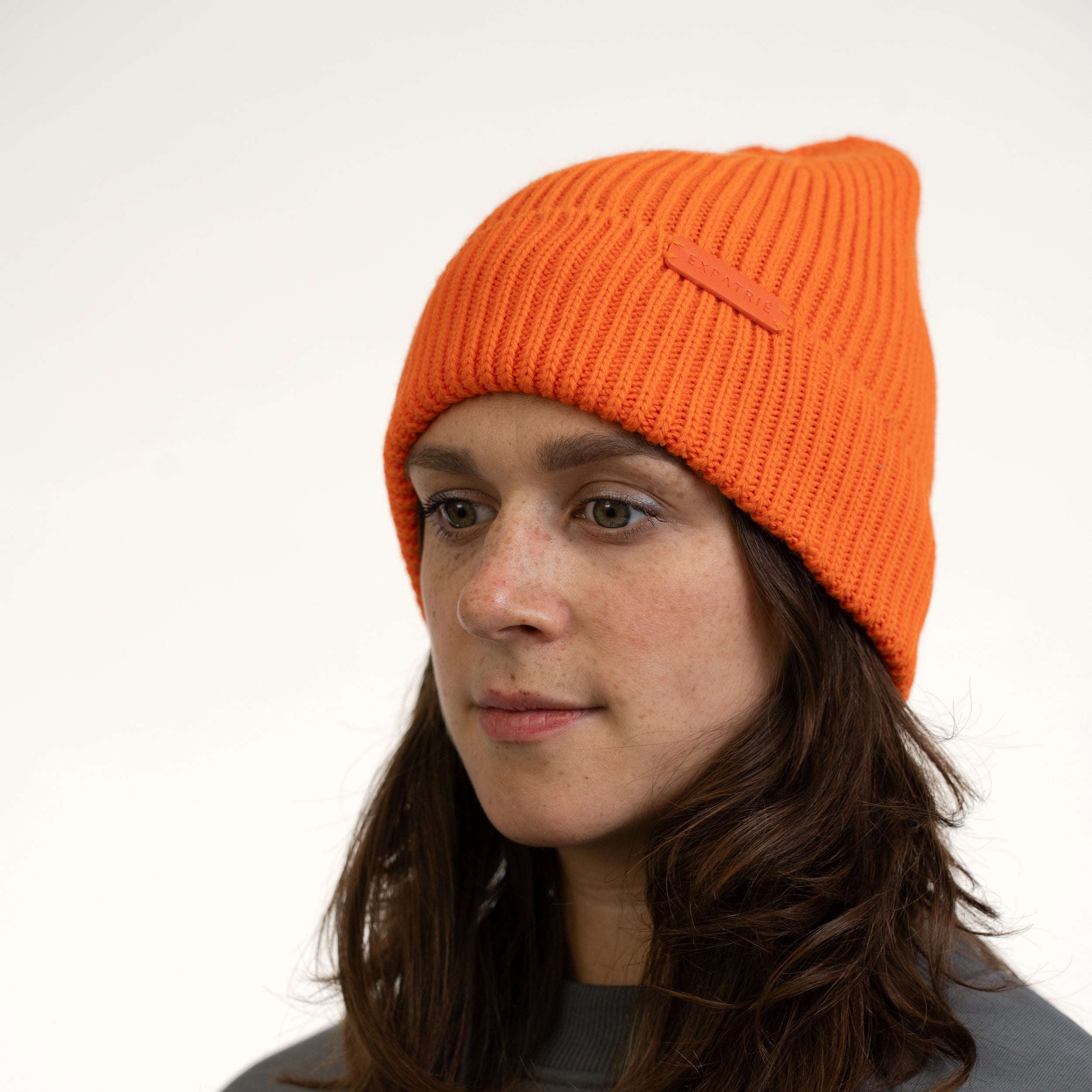 Frau trägt orangefarbene Strickmütze 'Mütze Luna' mit geripptem Design und kleinem Expatrié-Logo