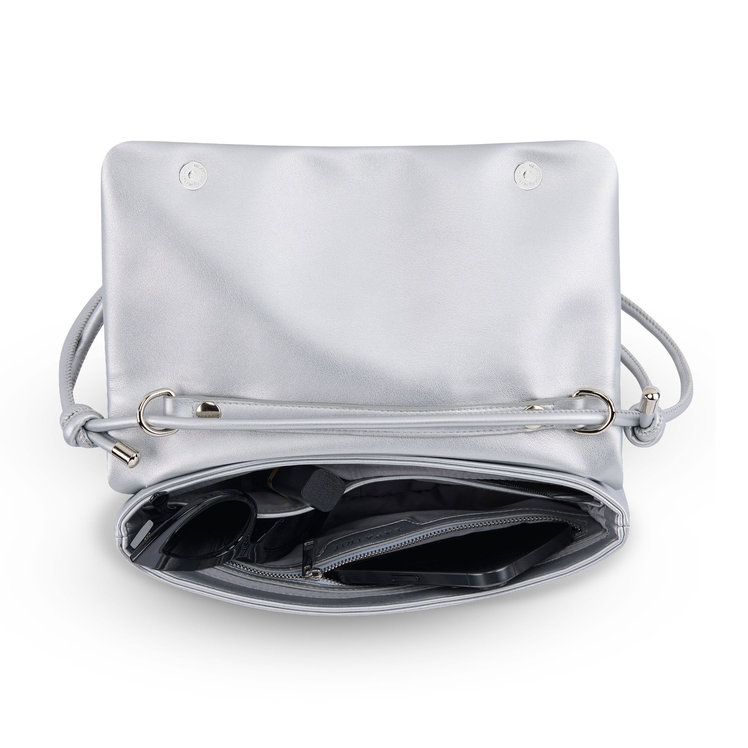 Silberne Clutch 'Juliette' aus Leder mit Reißverschlussfach und verstellbarem Schulterriemen, geöffnet und mit Sonnenbrille und Handy gefüllt