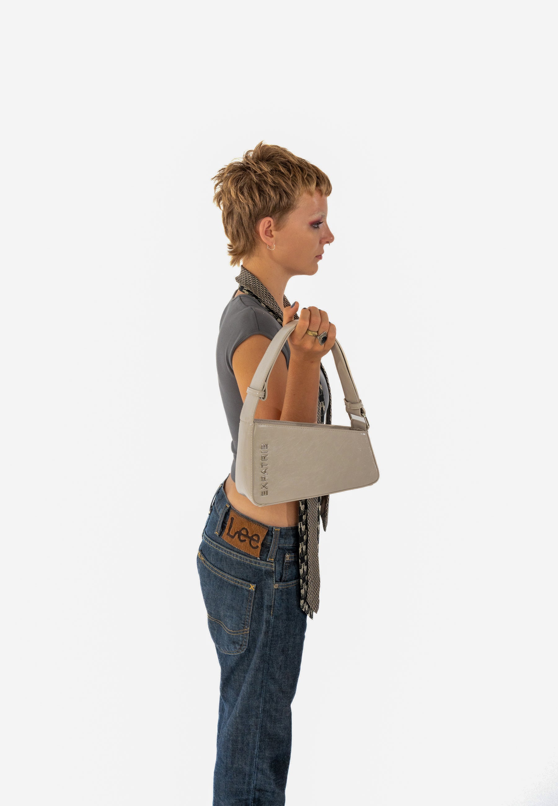 Frau mit kurzem Haar hält beige Handtasche GEORGIA von Expatrié seitlich