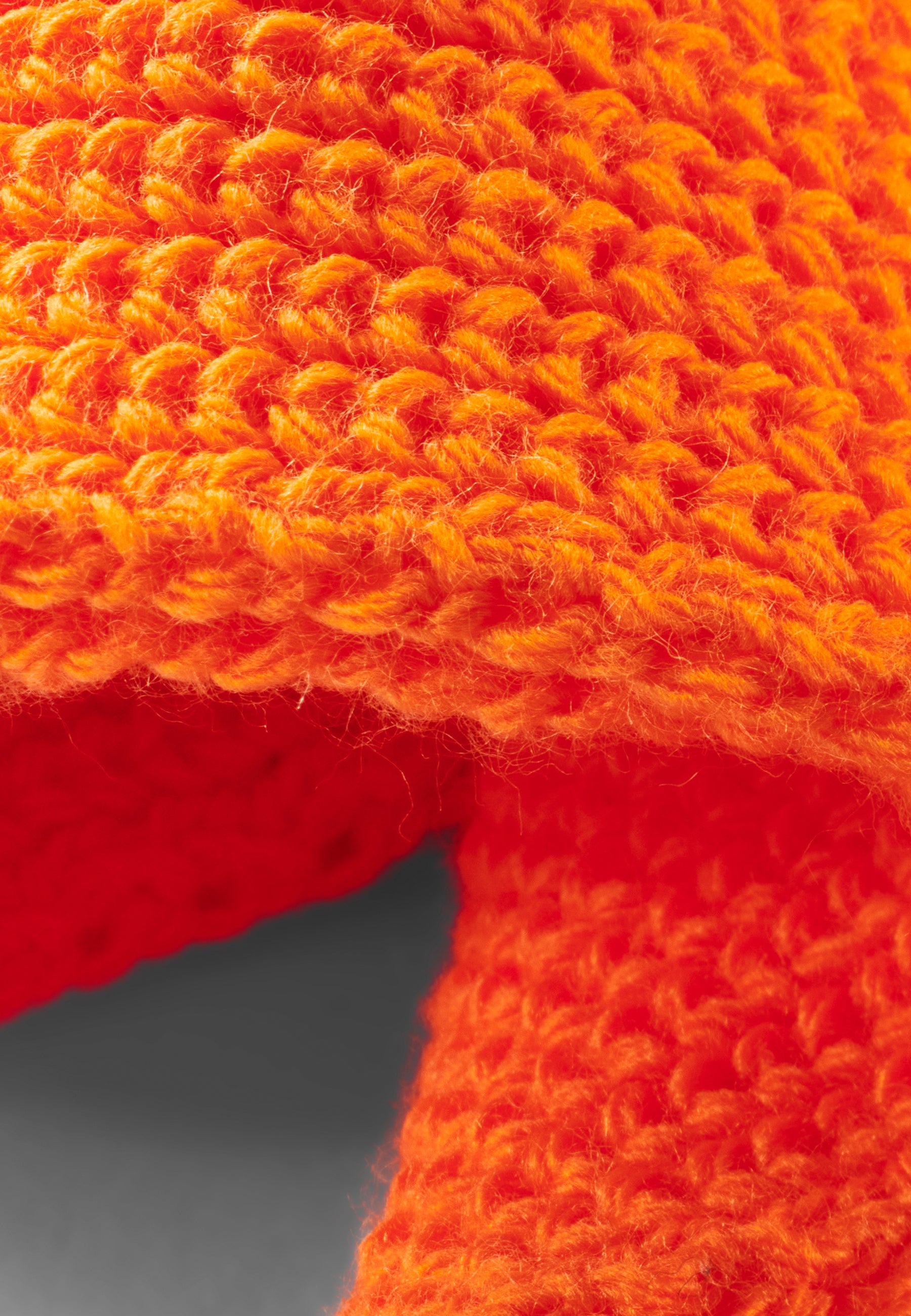 Nahaufnahme eines gestrickten orangefarbenen Schals aus dickem Garn