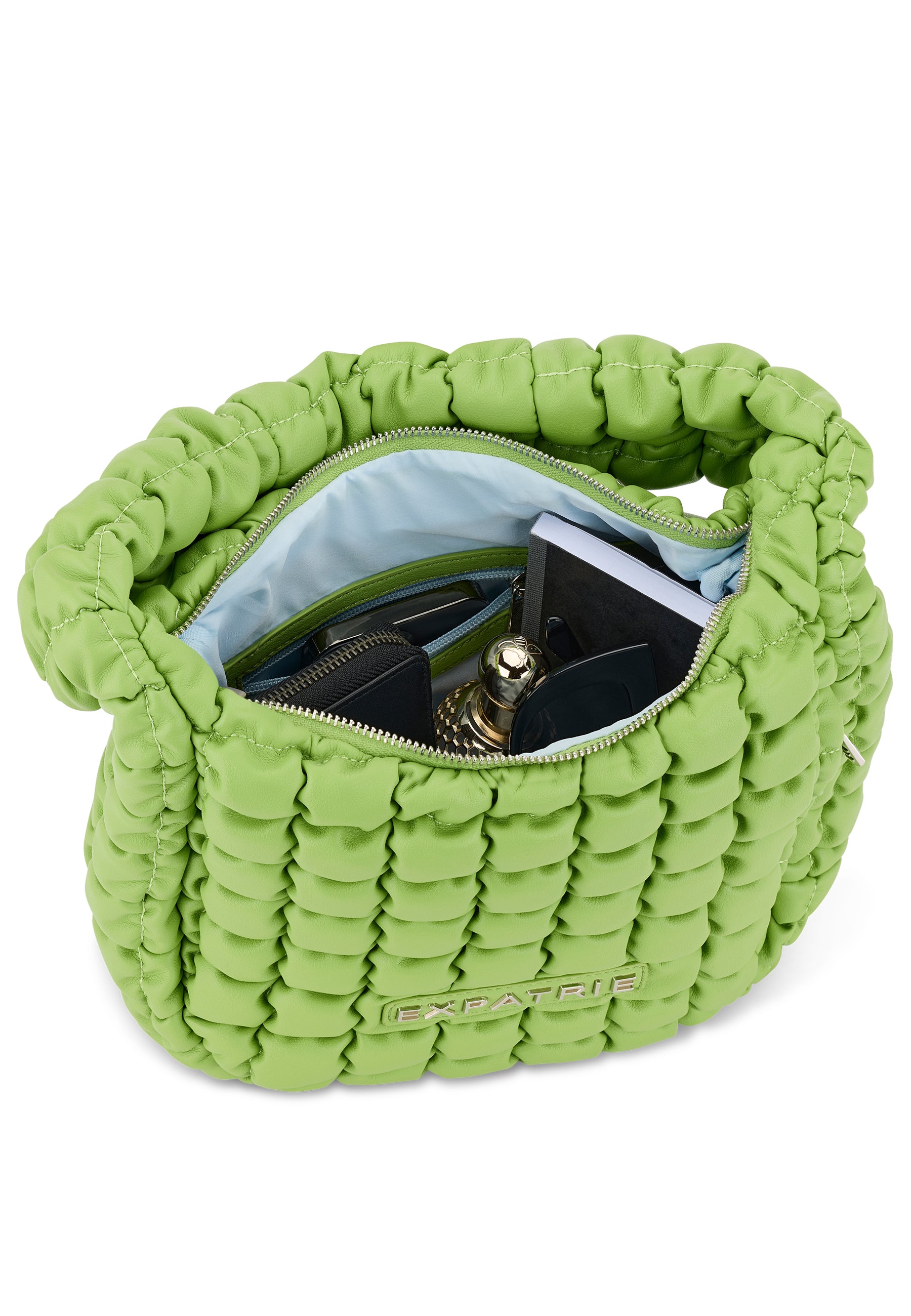 Grüne gesteppte PIPPA LARGE Handtasche von Expatrié mit geöffneter Reißverschlussöffnung und sichtbarem Innenfach mit Kosmetik, Brille und Notizbuch