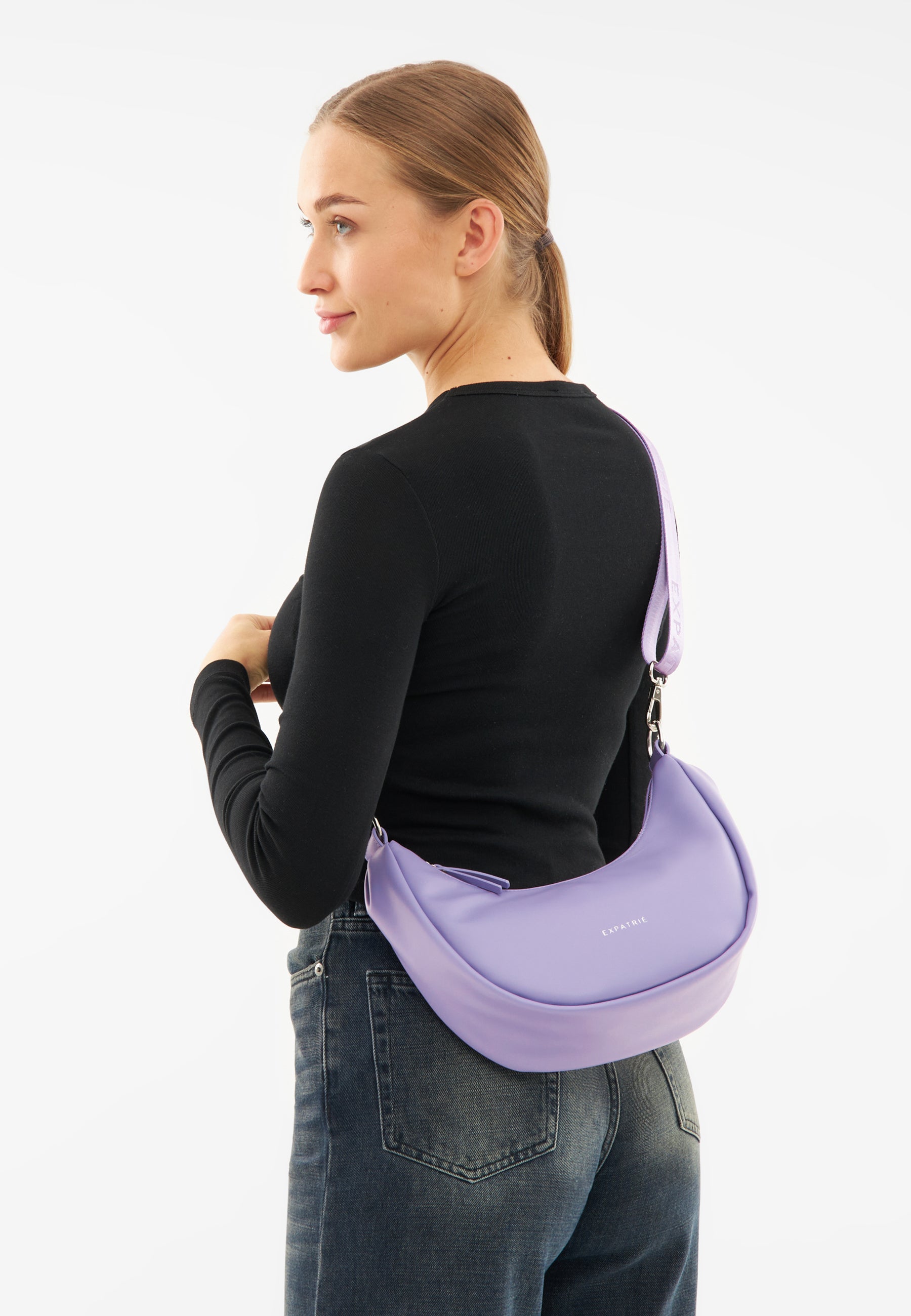 Frau trägt schwarze Langarmshirt und blaue Jeans mit lila LEA SMALL Half Moon Bag über der Schulter