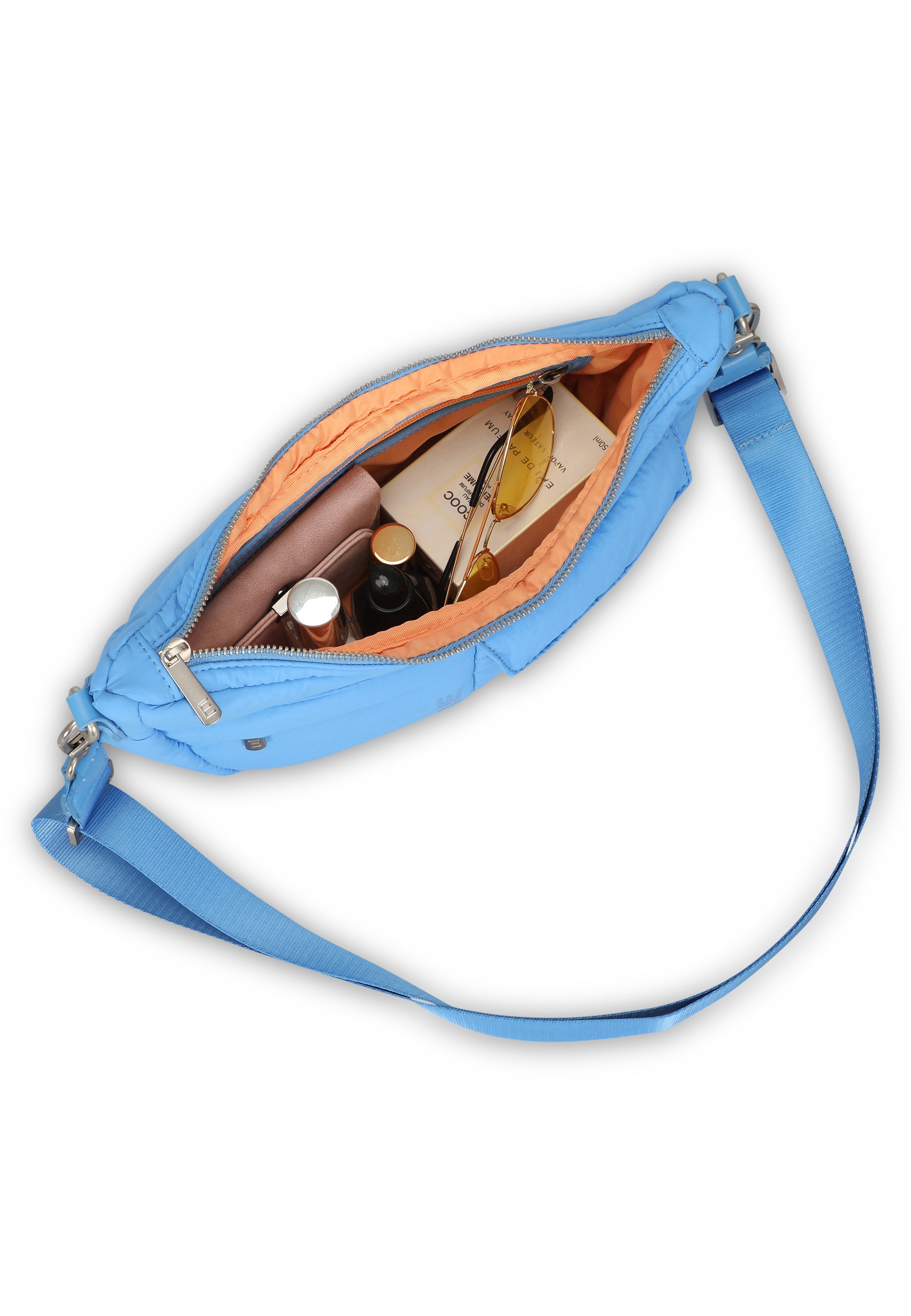 VIVY Half Moon Bag in Blau mit orangefarbenem Innenfutter, offen mit Sonnenbrille, Parfüm und Buch gefüllt