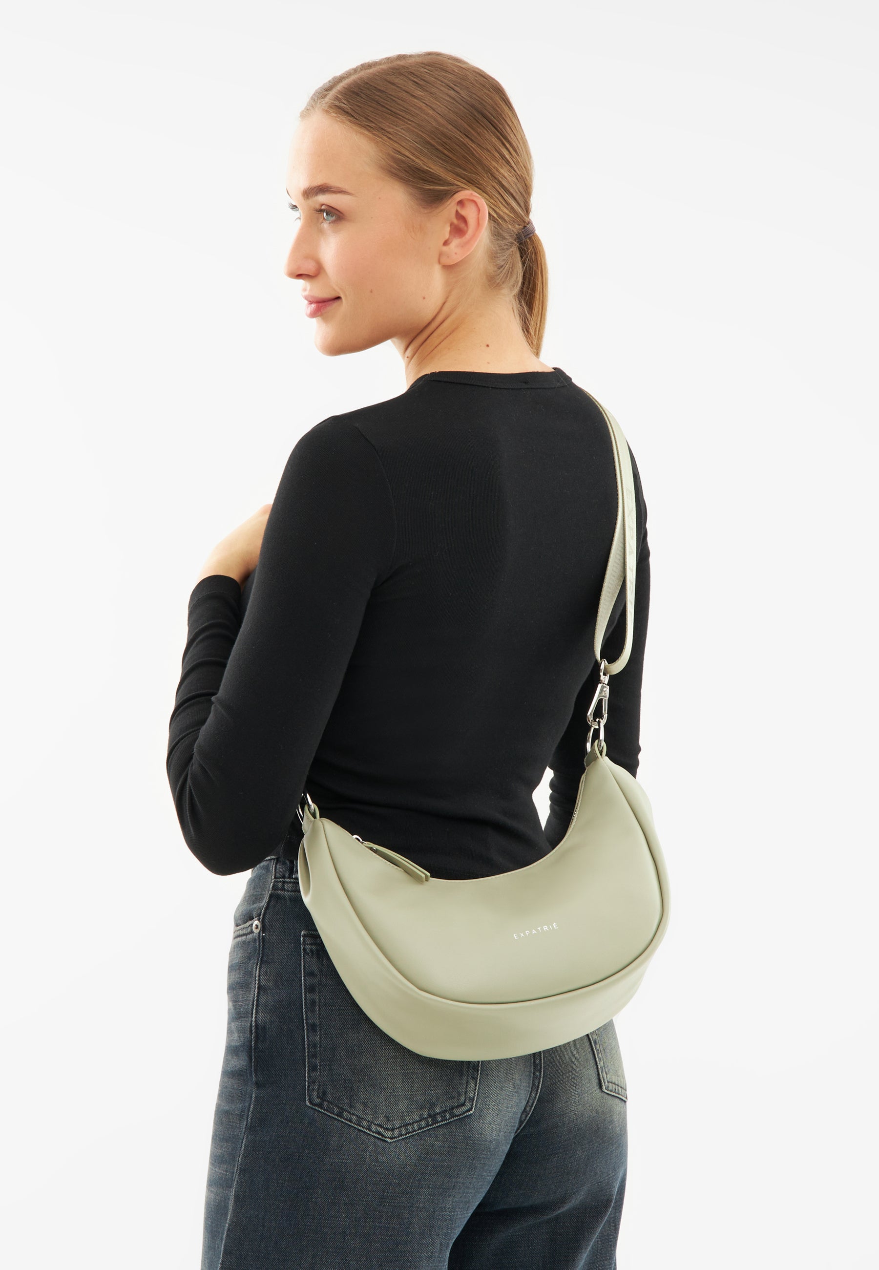 Frau trägt LEA SMALL Half Moon Bag in blassem Grün über der Schulter