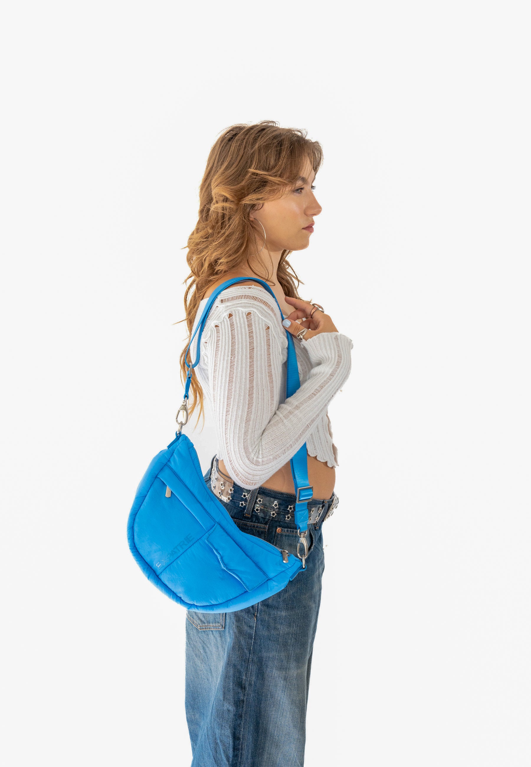 Frau trägt VIVY Halbmonden-Tasche in königsblau über der Schulter mit weißem Pullover und Jeans