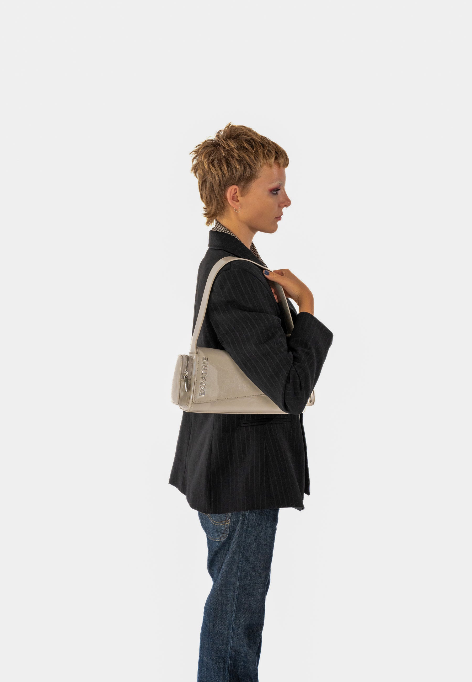 Person trägt beige GRACE Handtasche über der Schulter, kombiniert mit schwarzem Blazer und Jeans