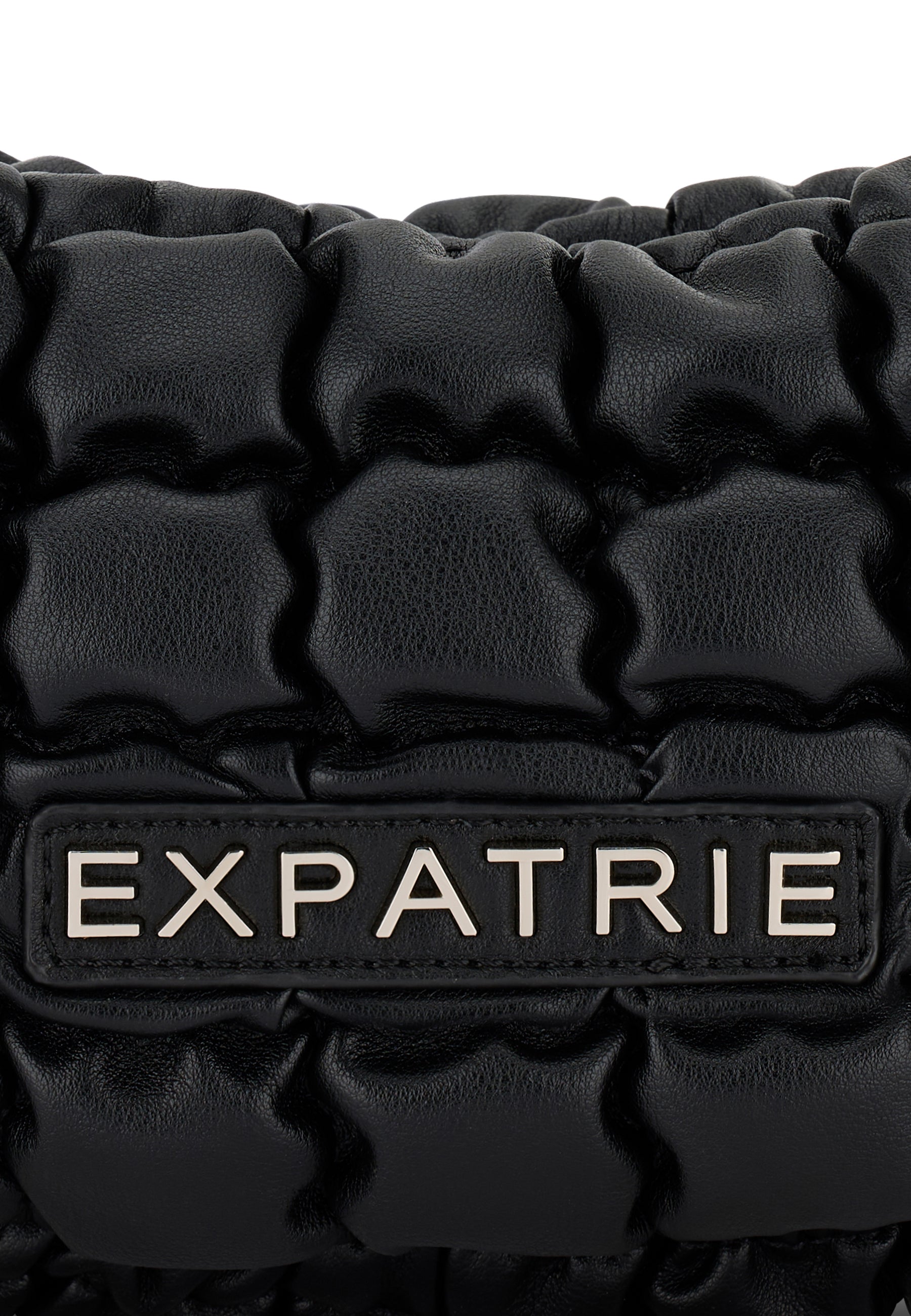 Naheinstellung der gesteppten schwarzen PIPPA SMALL Handtasche mit metallischem 'EXPATRIE' Logo