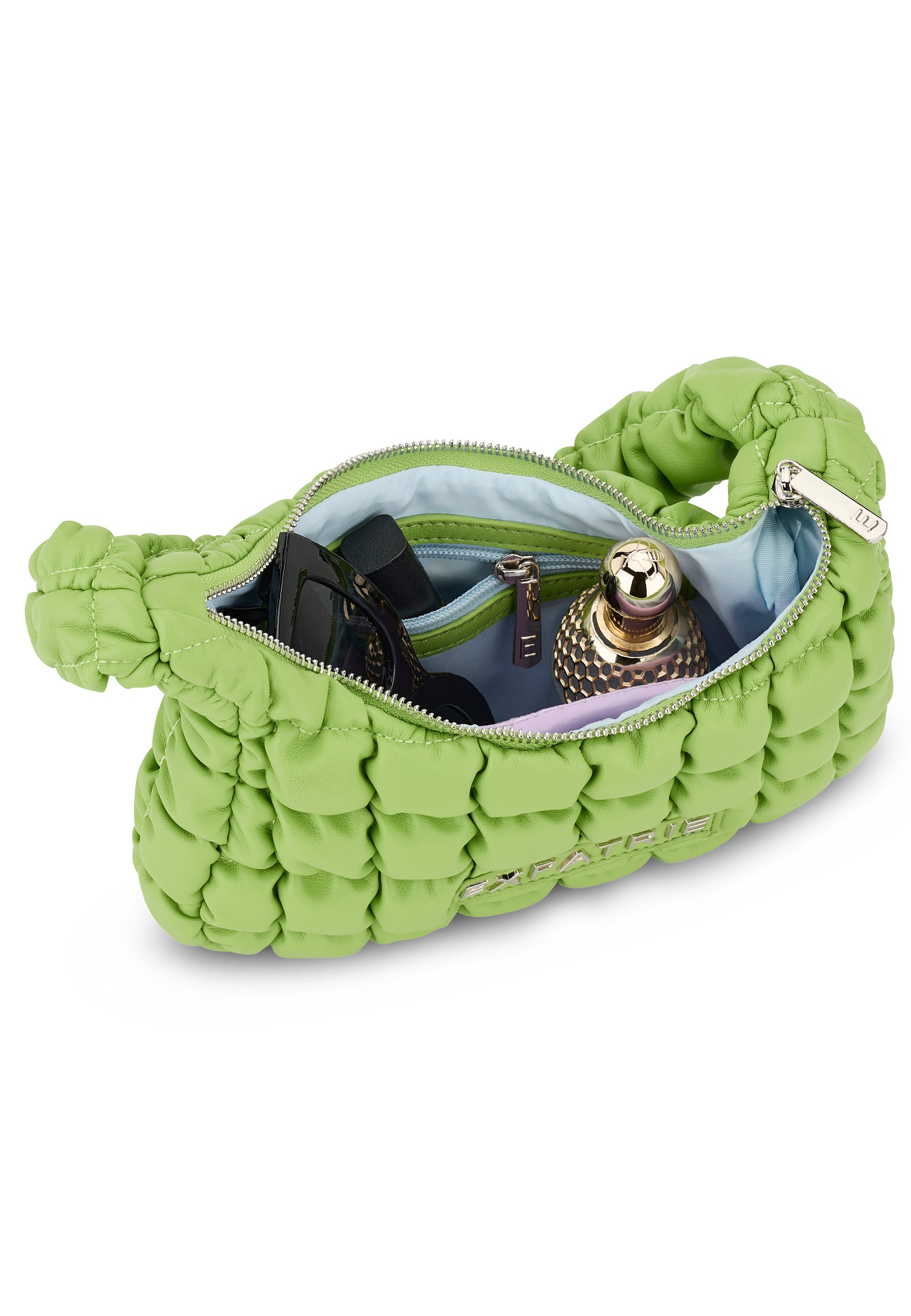 Grüne PIPPA SMALL Handtasche mit geworfenem Muster, geöffnet und mit Sonnenbrille und Parfümflasche gefüllt