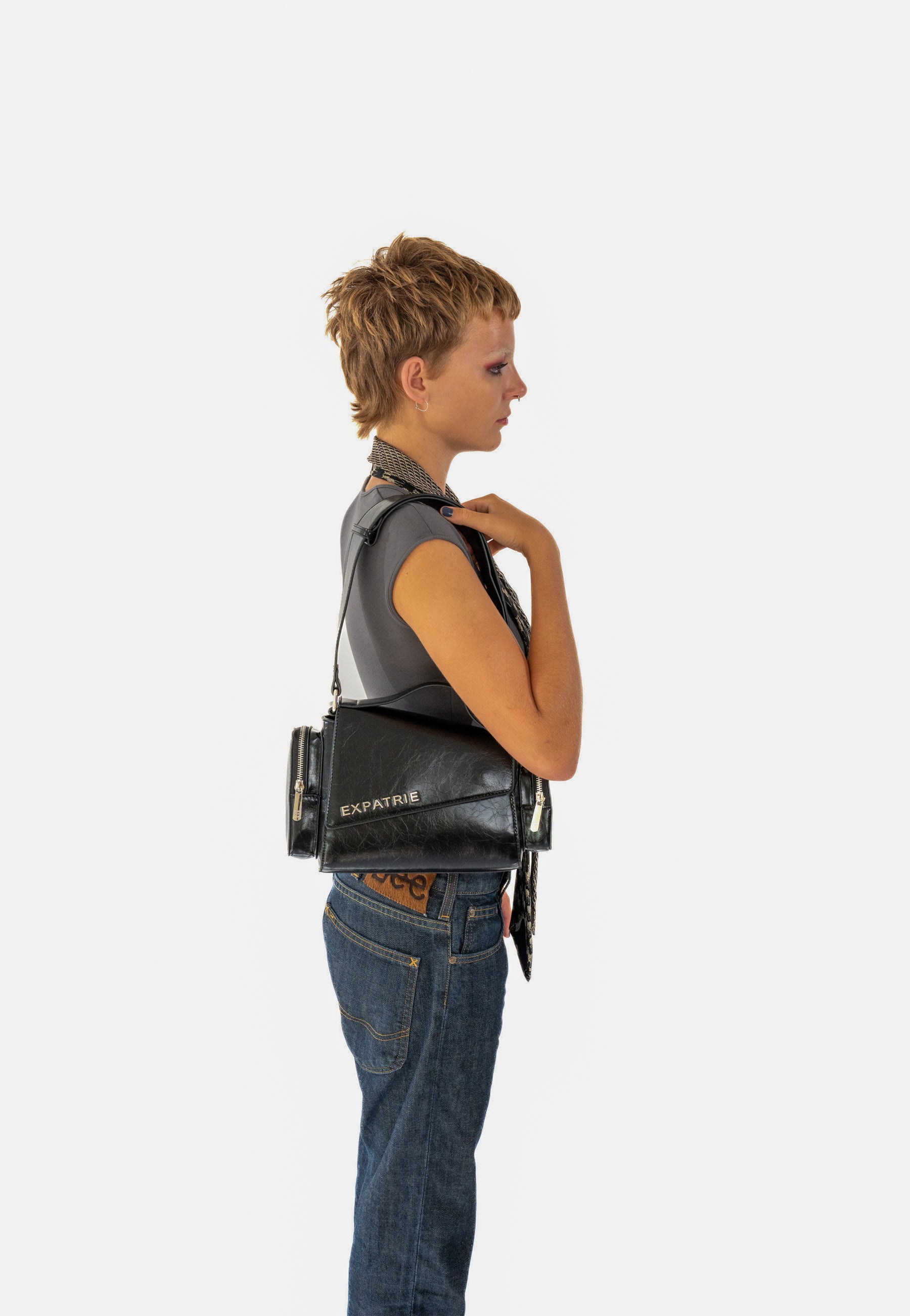 Seitliche Ansicht einer Frau mit kurzem Haar, die eine schwarze HUNTER Handtasche von Expatrié trägt