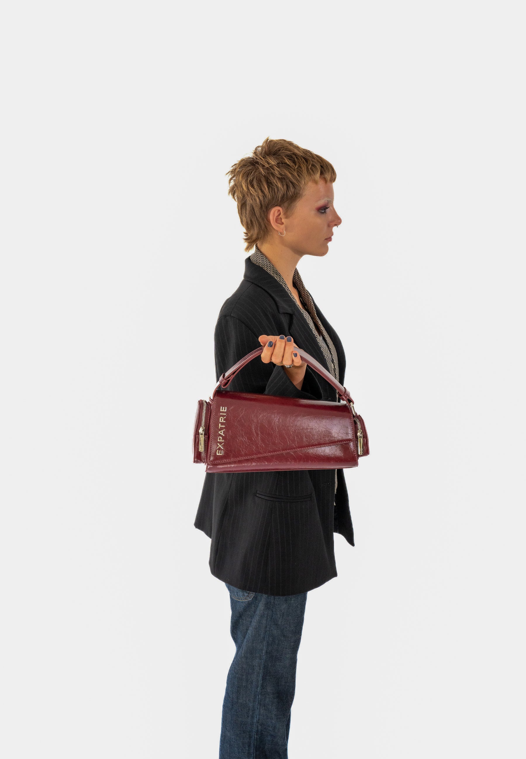 Frau mit kurzem Haar trägt weinrote Handtasche 'GRACE' von Expatrié im Vintage-Stil