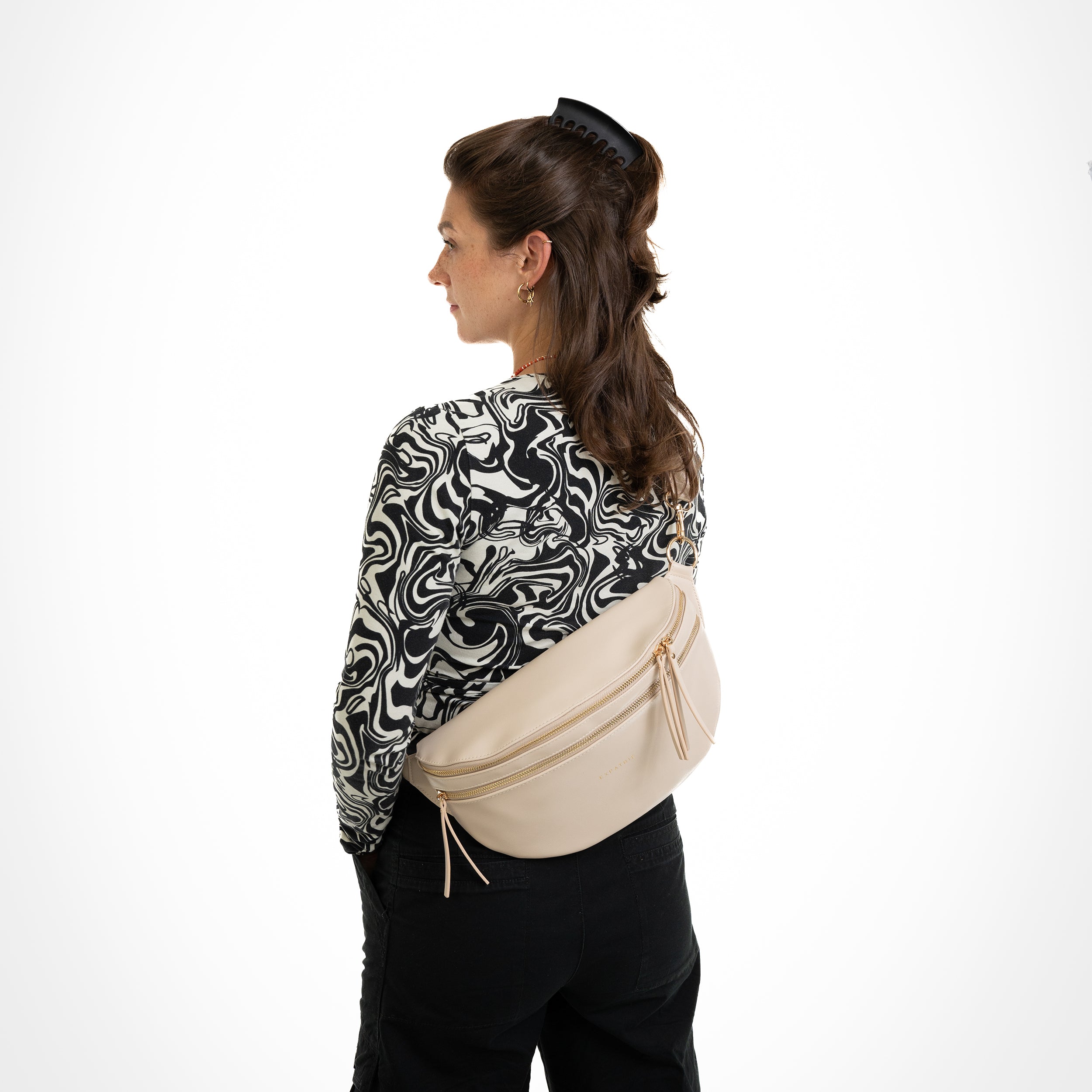 Frau von hinten mit schwarzer und weiß gemustertem Oberteil, trägt beige Ledertasche Bauchtasche Alice Large quer am Rücken