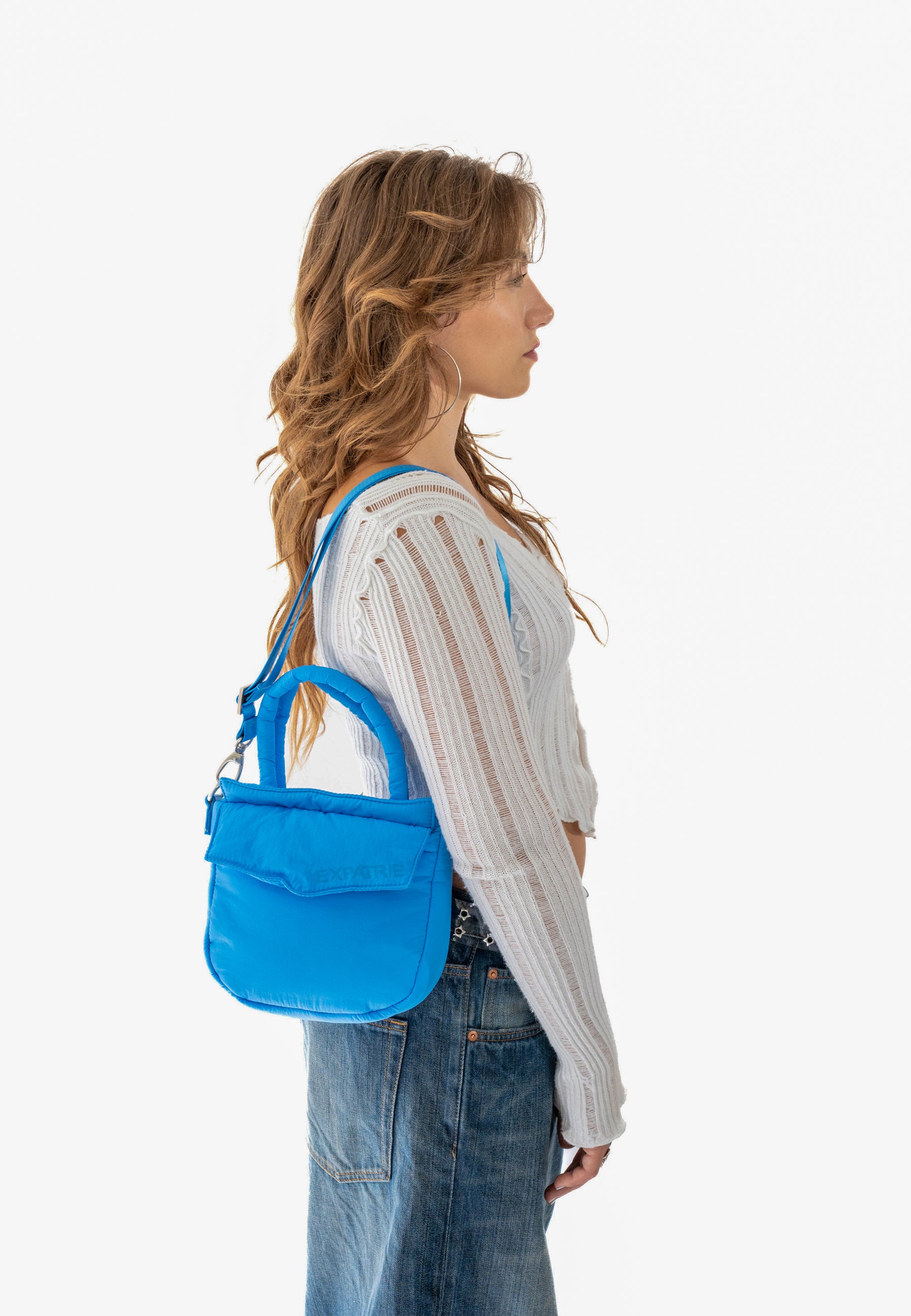 Frau im Profil mit moderner, royalblauer POPPY SMALL Handtasche über der Schulter