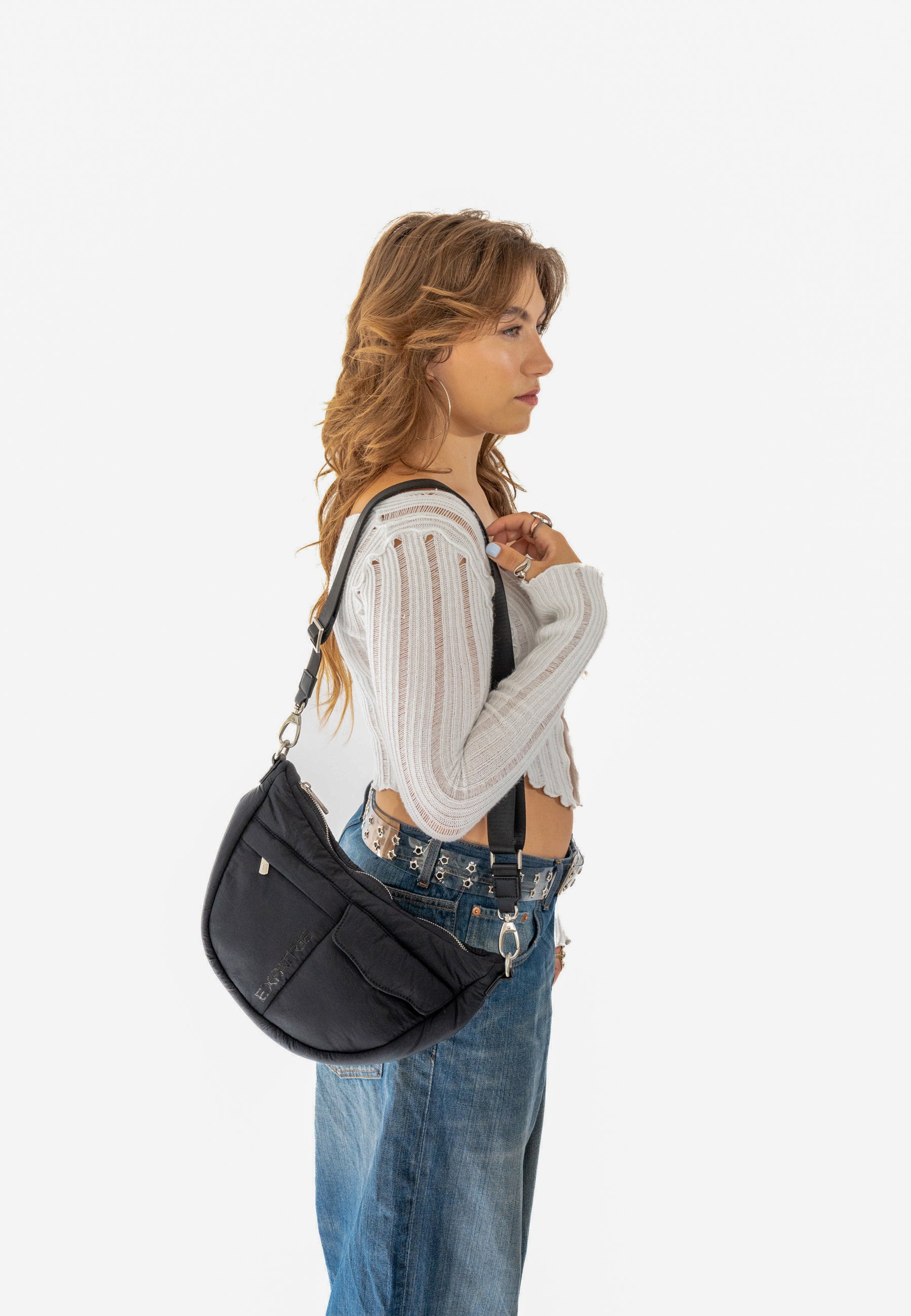 Frau trägt die schwarze VIVY Half Moon Tasche über der Schulter, kombiniert mit weißem Feinstricktop und Jeans