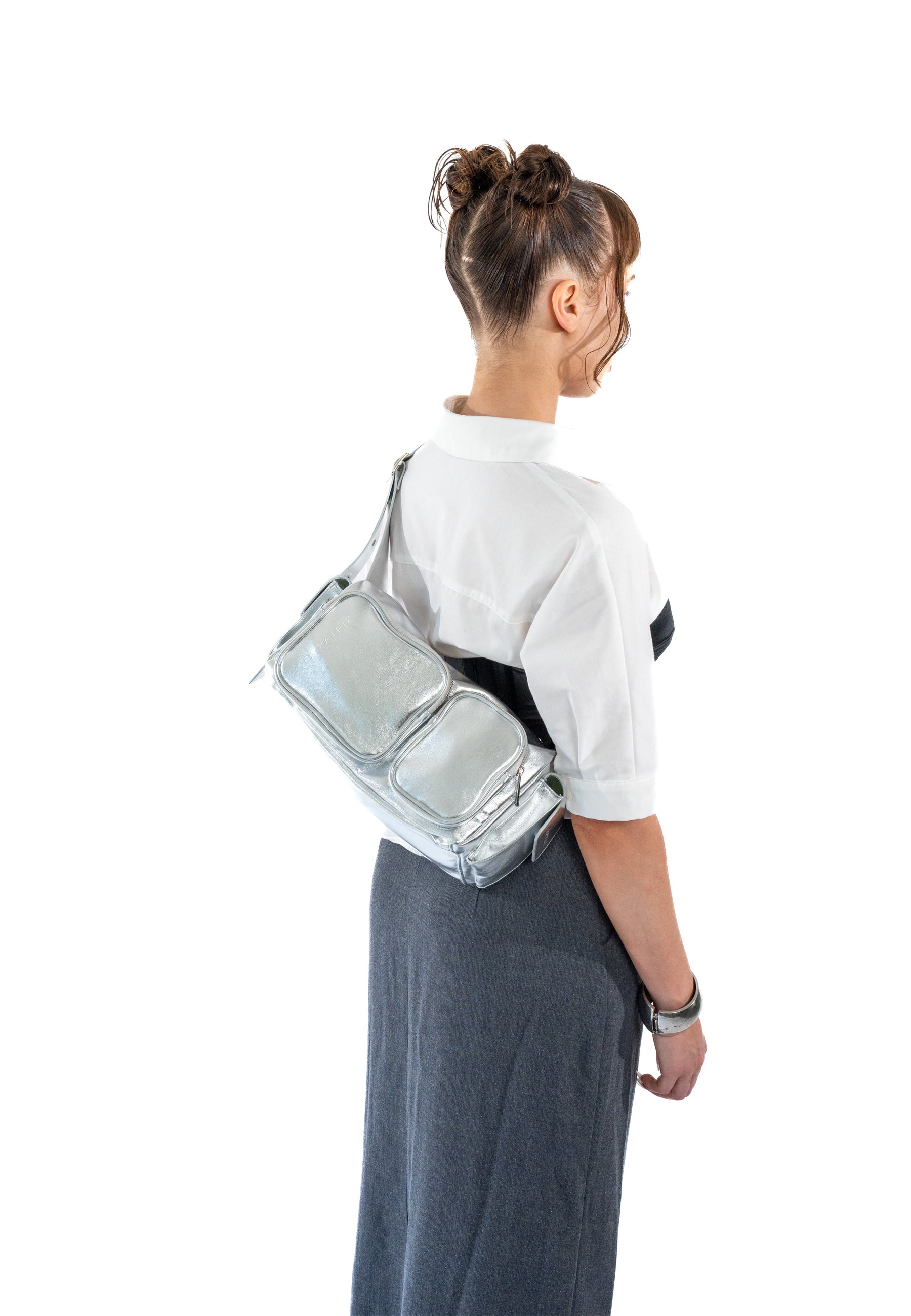 Frau trägt silberne STELLA Schultertasche mit zwei Fronttaschen, weiße Bluse und grauer Rock