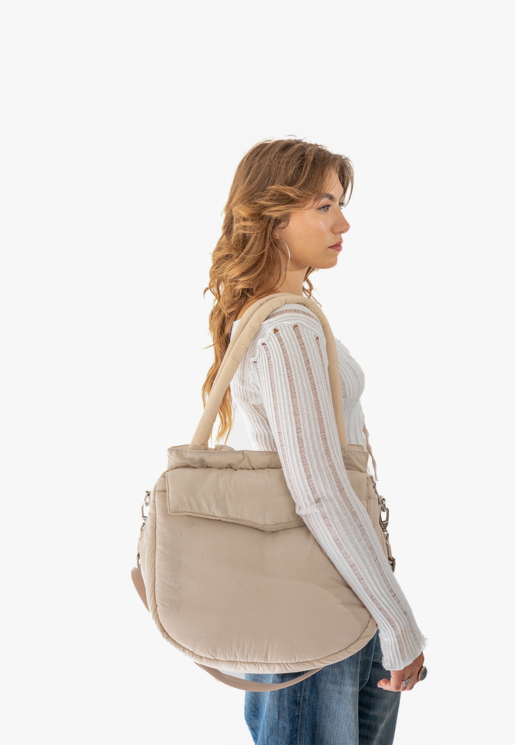 Beige Shopper Tasche 'POPPY' aus weichem Material an der Schulter einer Frau mit weißem, langärmligem Pullover