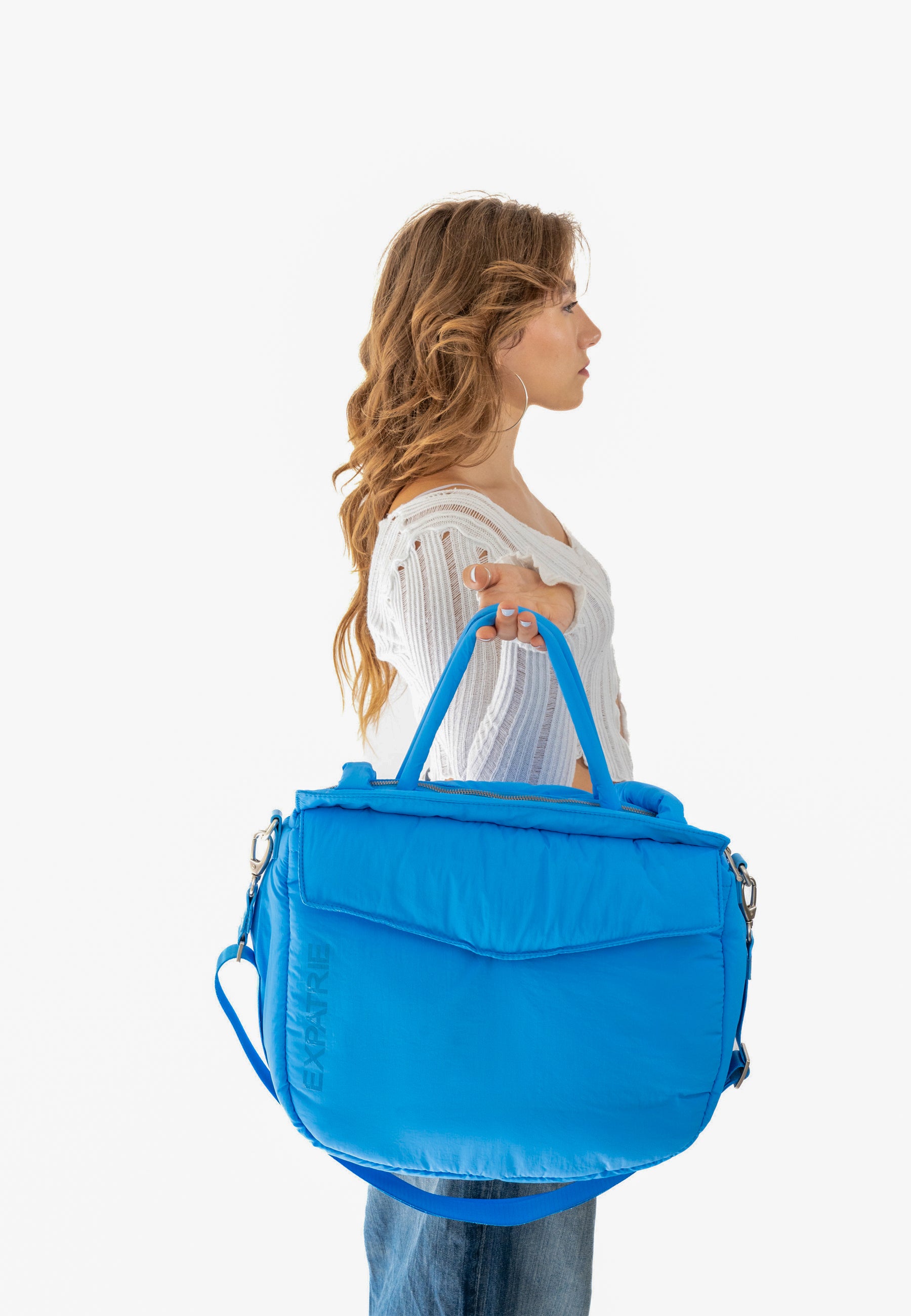 Frau hält blaue POPPY Shopper Tasche von Expatrié, seitliche Ansicht