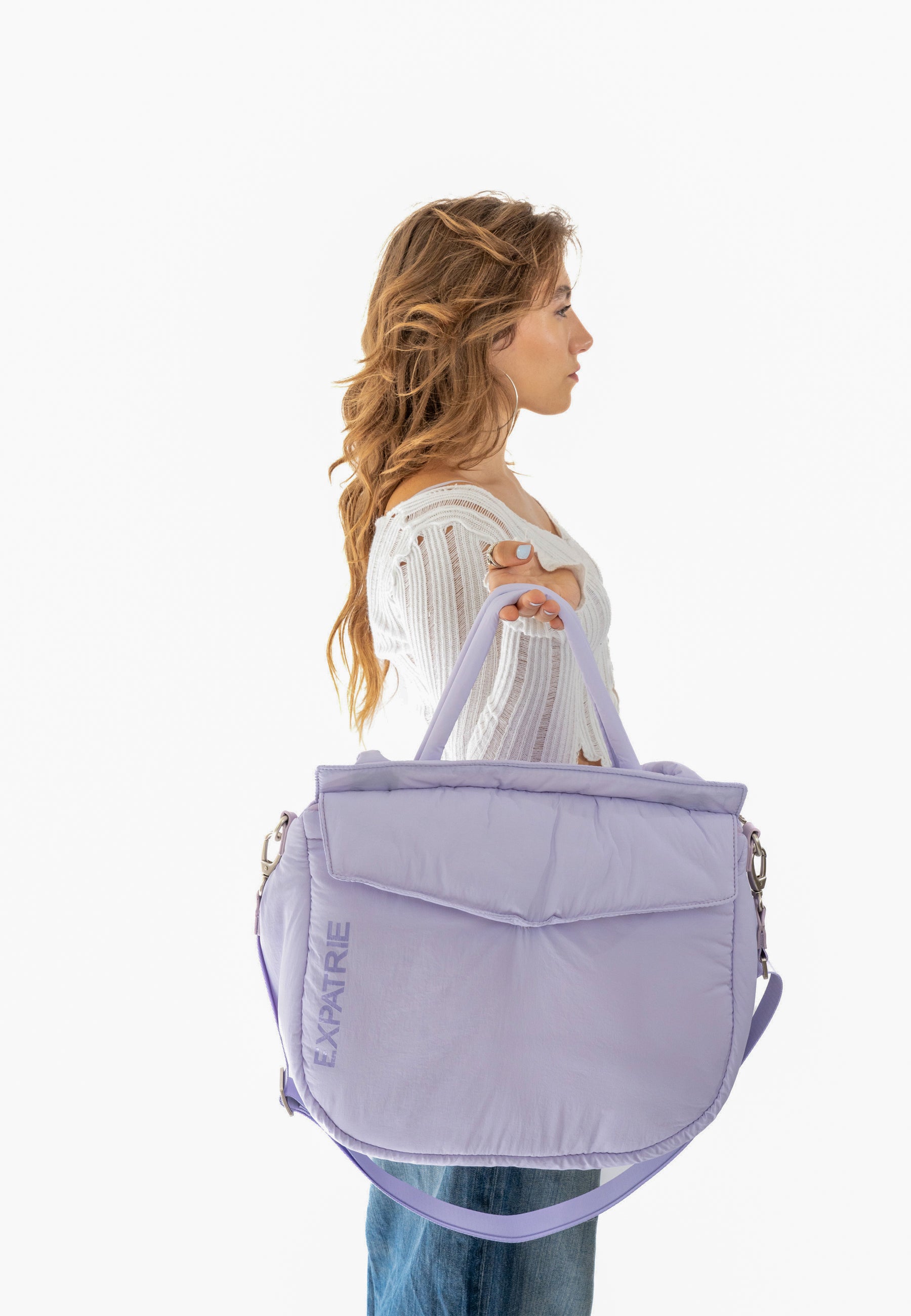 Frau hält fliederfarbene Poppy Shopper Tasche von Expatrié, seitlich fotografiert