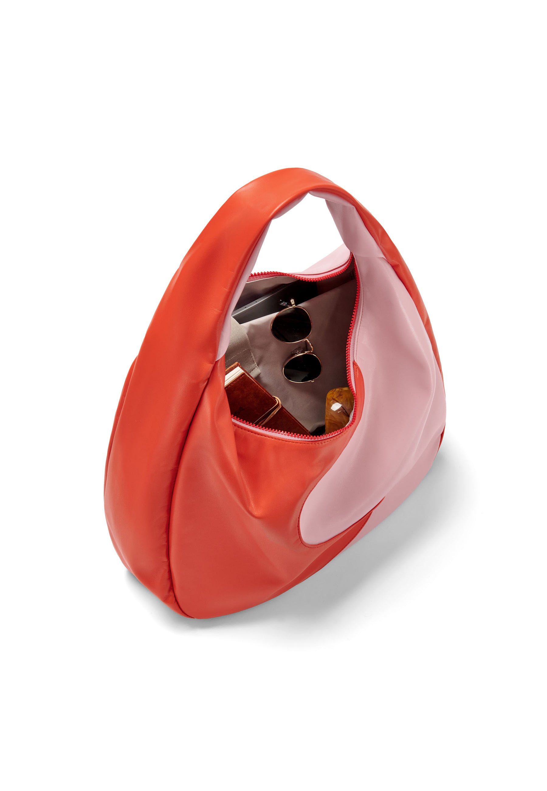 LINA Schultertasche in zweifarbigem rot und rosa mit Reißverschluss, geöffnet und mit Sonnenbrille und Kosmetik gefüllt