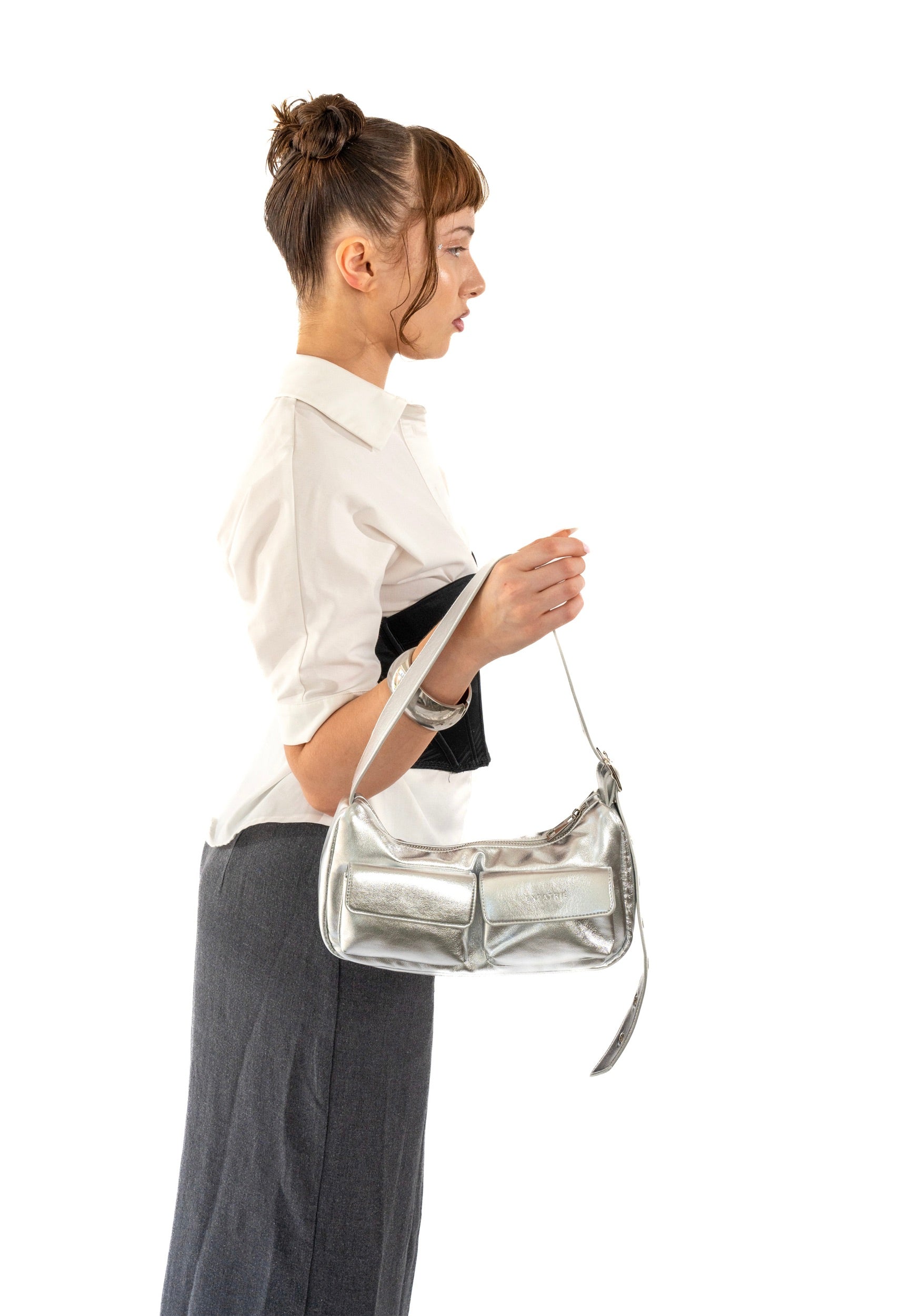 Profil einer Frau mit hochgesteckten braunen Haaren, die eine silber-metallic 'ELECTRA' Handtasche trägt