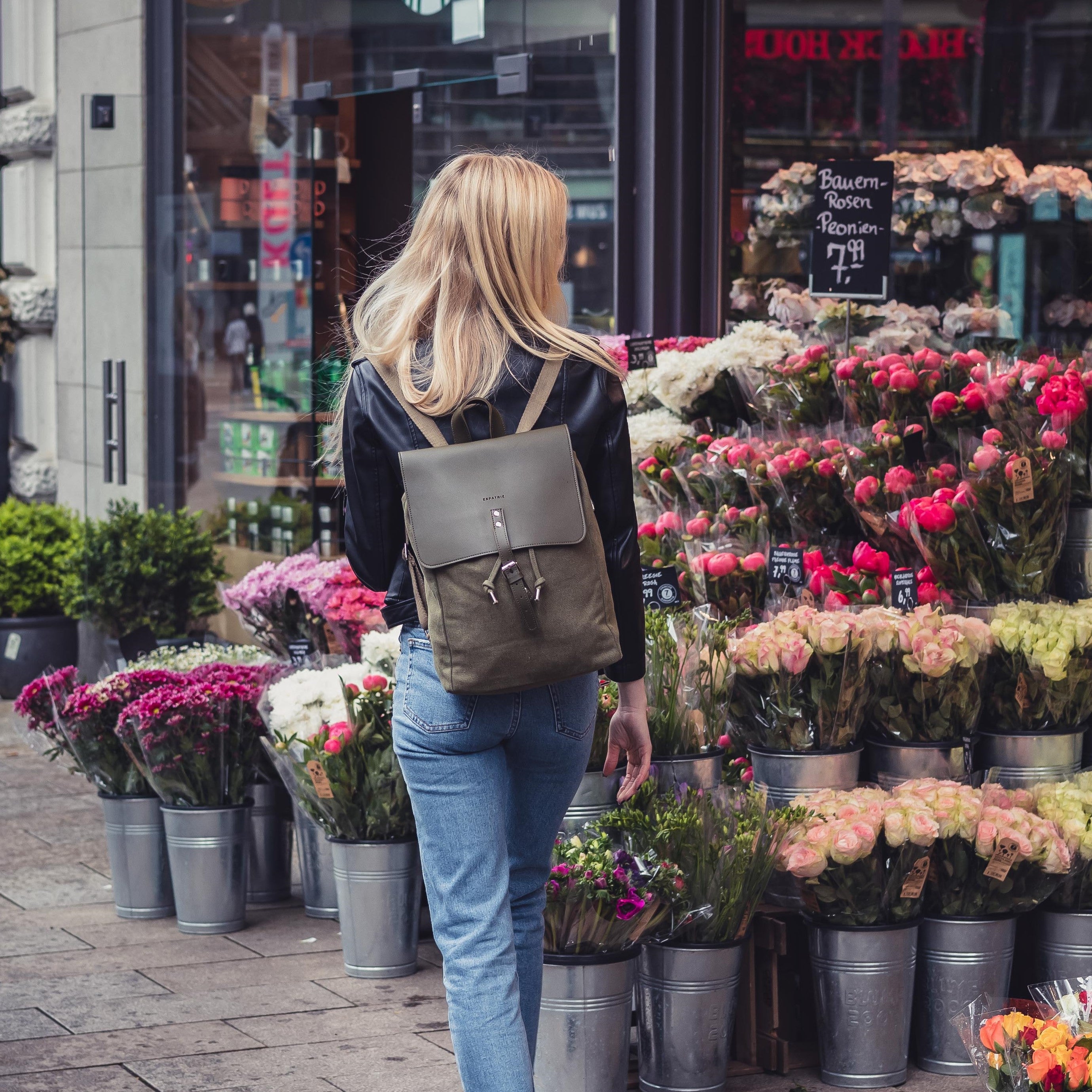 Frau mit Rucksack Anouk aus Canvas und Leder vor einem Blumenladen