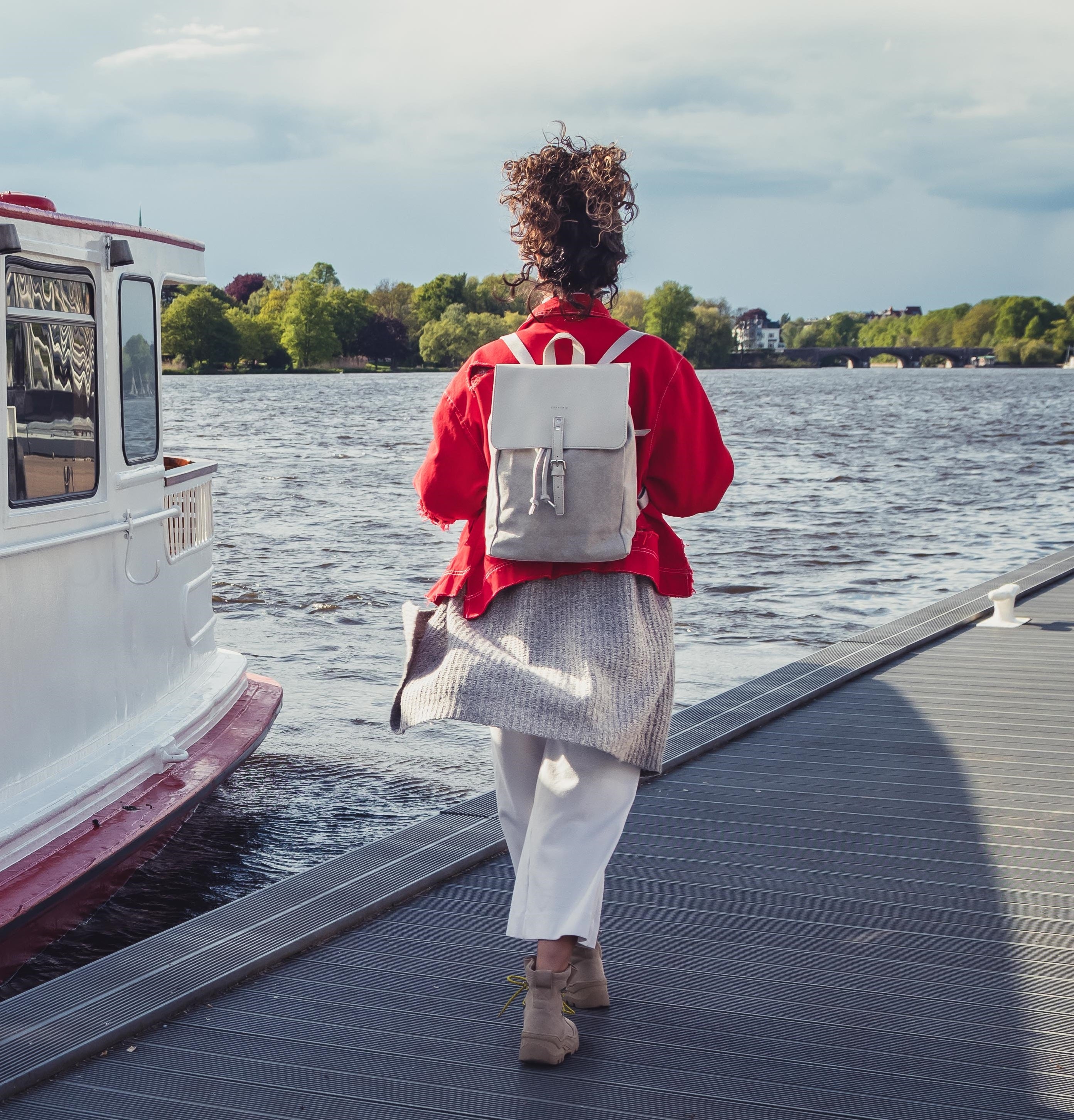 Frau mit grauem Canvas-Leder-Rucksack Anouk am Steg neben Wasser und Boot