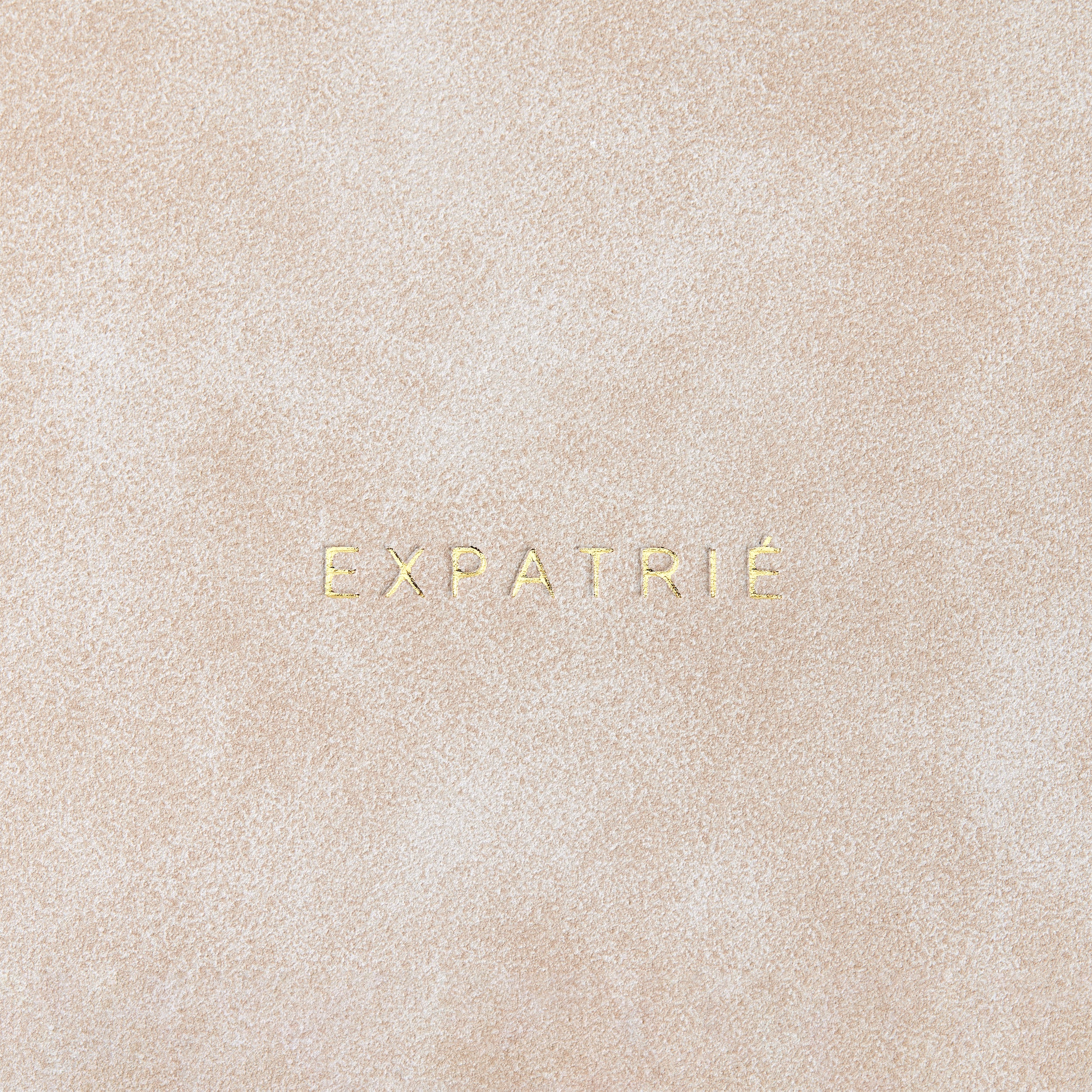 Beige Clutch Isabelle aus Kunstleder mit geprägtem Schriftzug 'EXPATRIÉ'