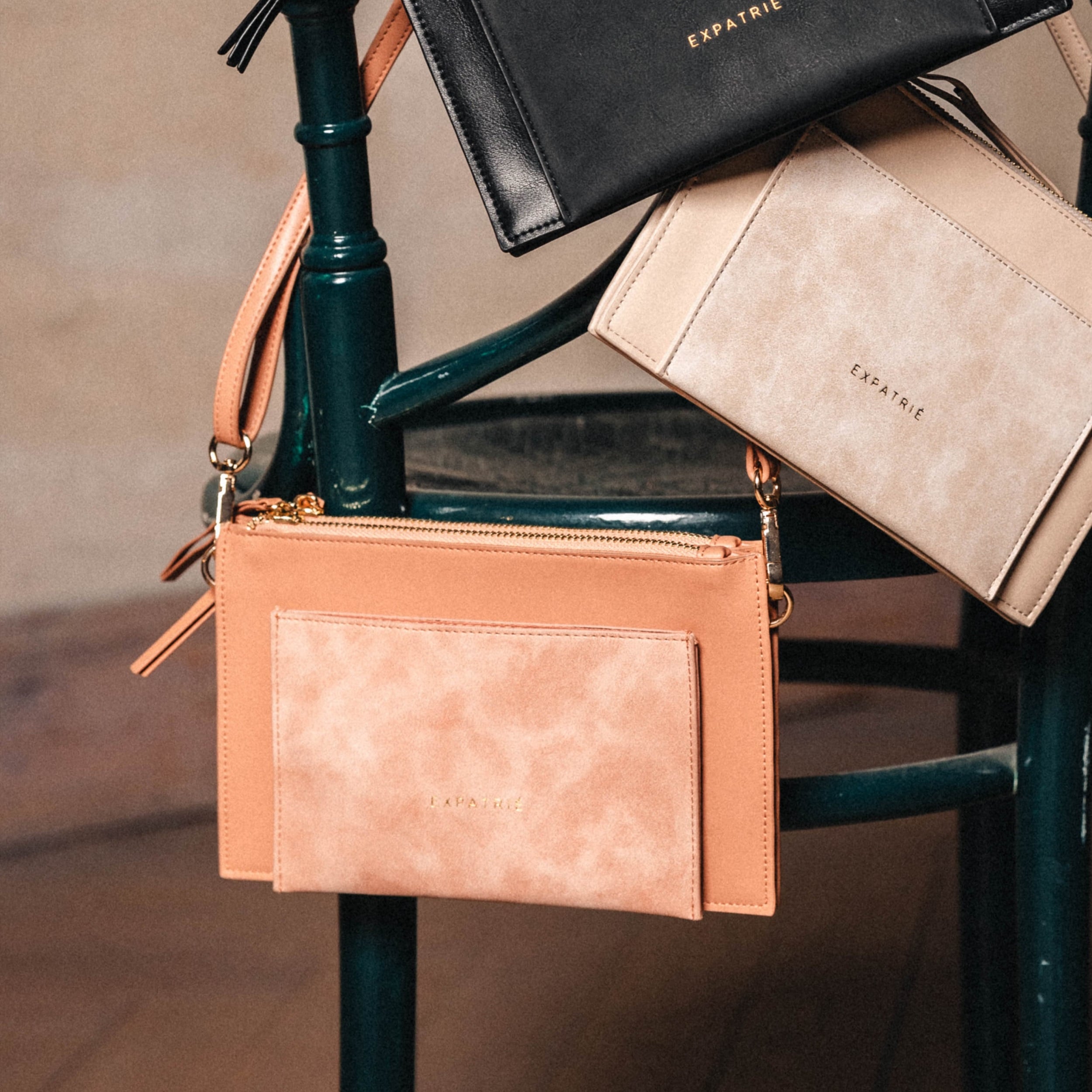 Rosa Clutch Isabelle von Expatrié mit Reißverschluss und abnehmbarem Träger an einem Stuhl