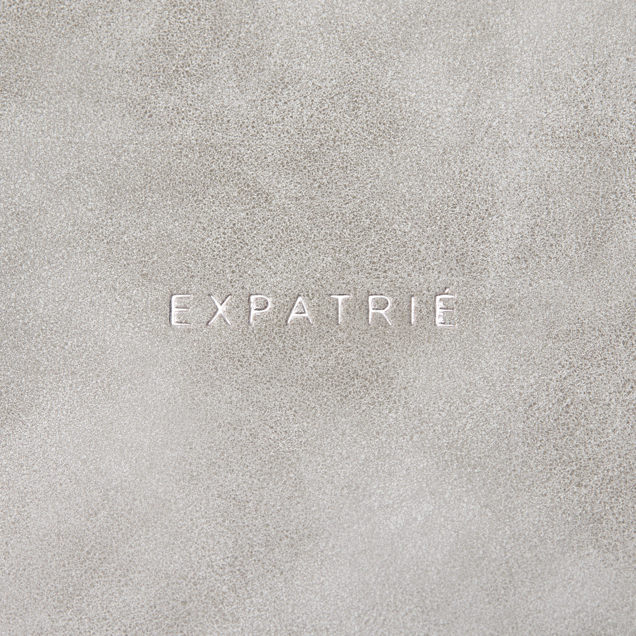 Logo ‚EXPATRIÉ‘ geprägt auf grauem Kunstleder der Saddle Bag Louise Large