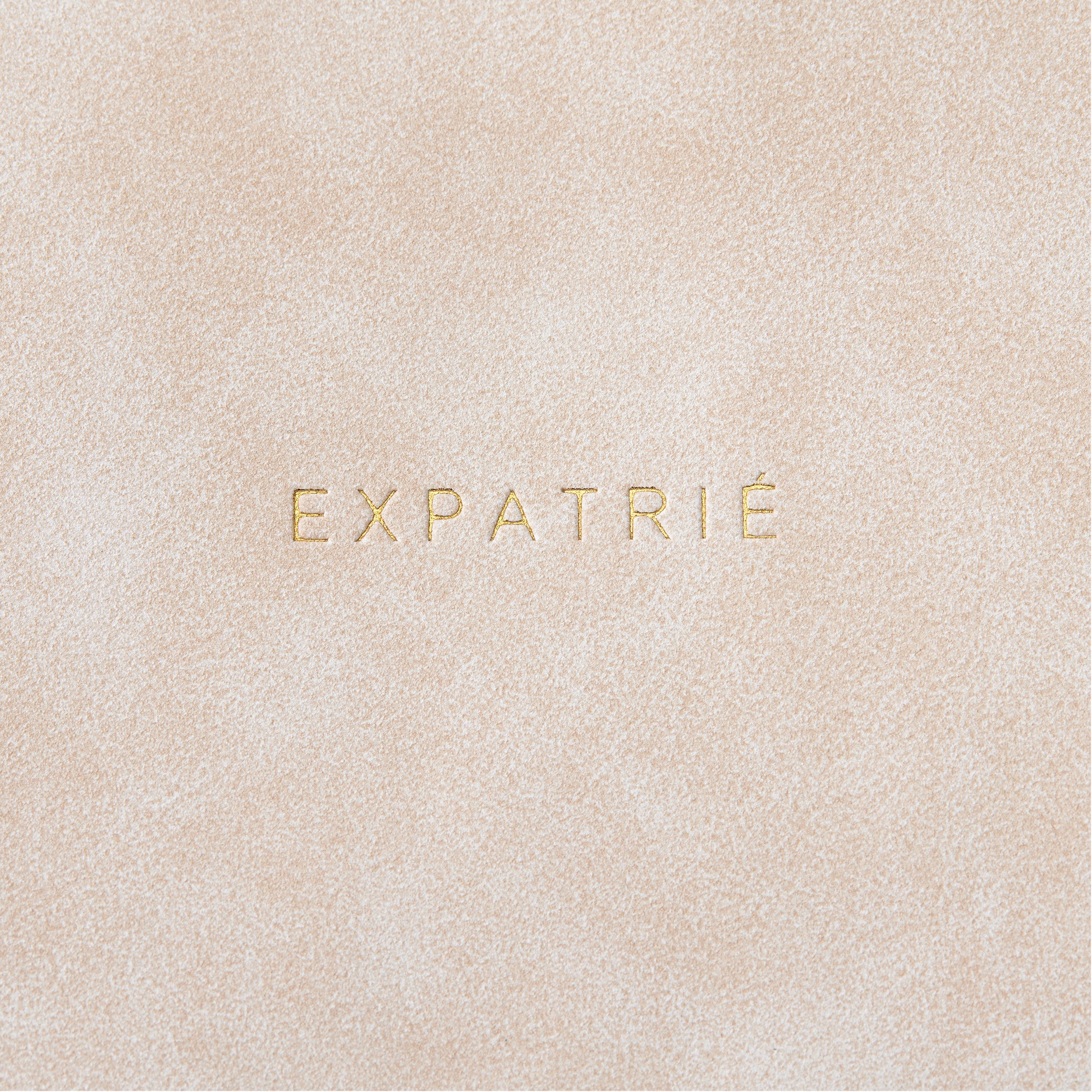 Beige Leder mit goldener Prägung 'EXPATRIÉ'