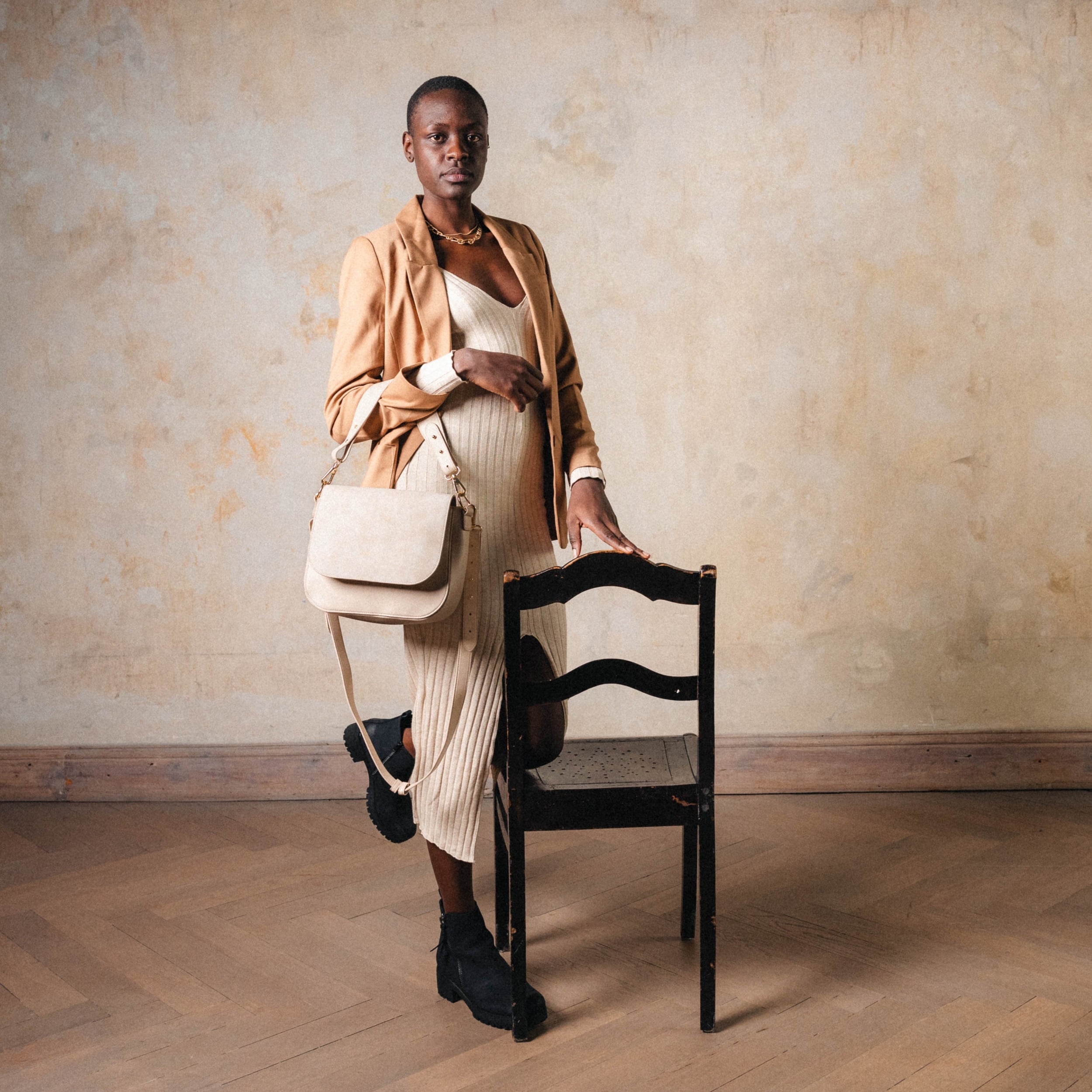 Schwangere Frau trägt beige Saddle Bag Louise Large Tasche, kombiniert mit beigem Kleid und Jacke