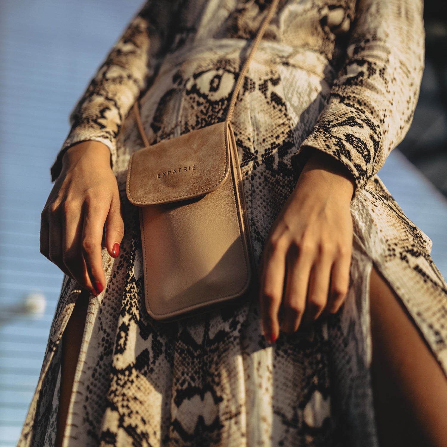 Beige Handy-Umhängetasche Amelie von Expatrié an Frau mit Schlangenmuster-Kleid