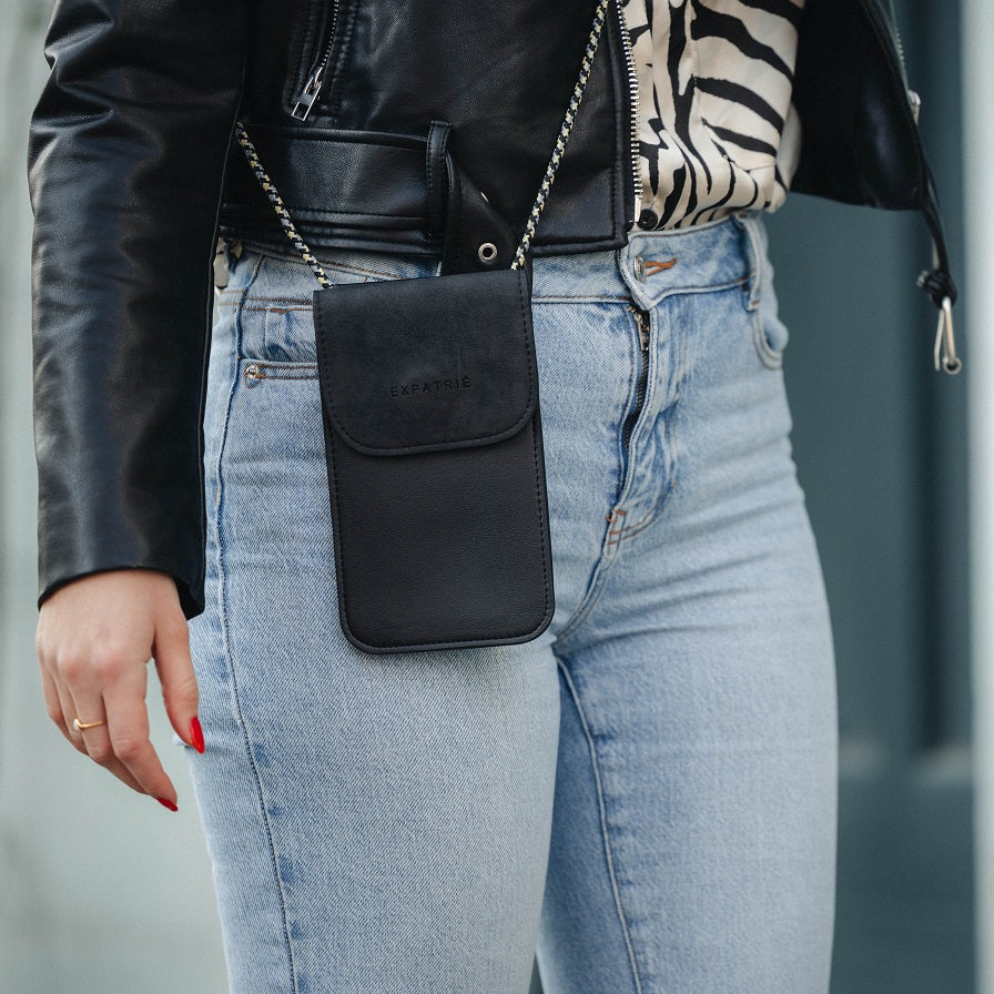 Kleine schwarze Umhängetasche Amelie für Handy aus Leder mit Kordel an Frau in Jeans und Lederjacke