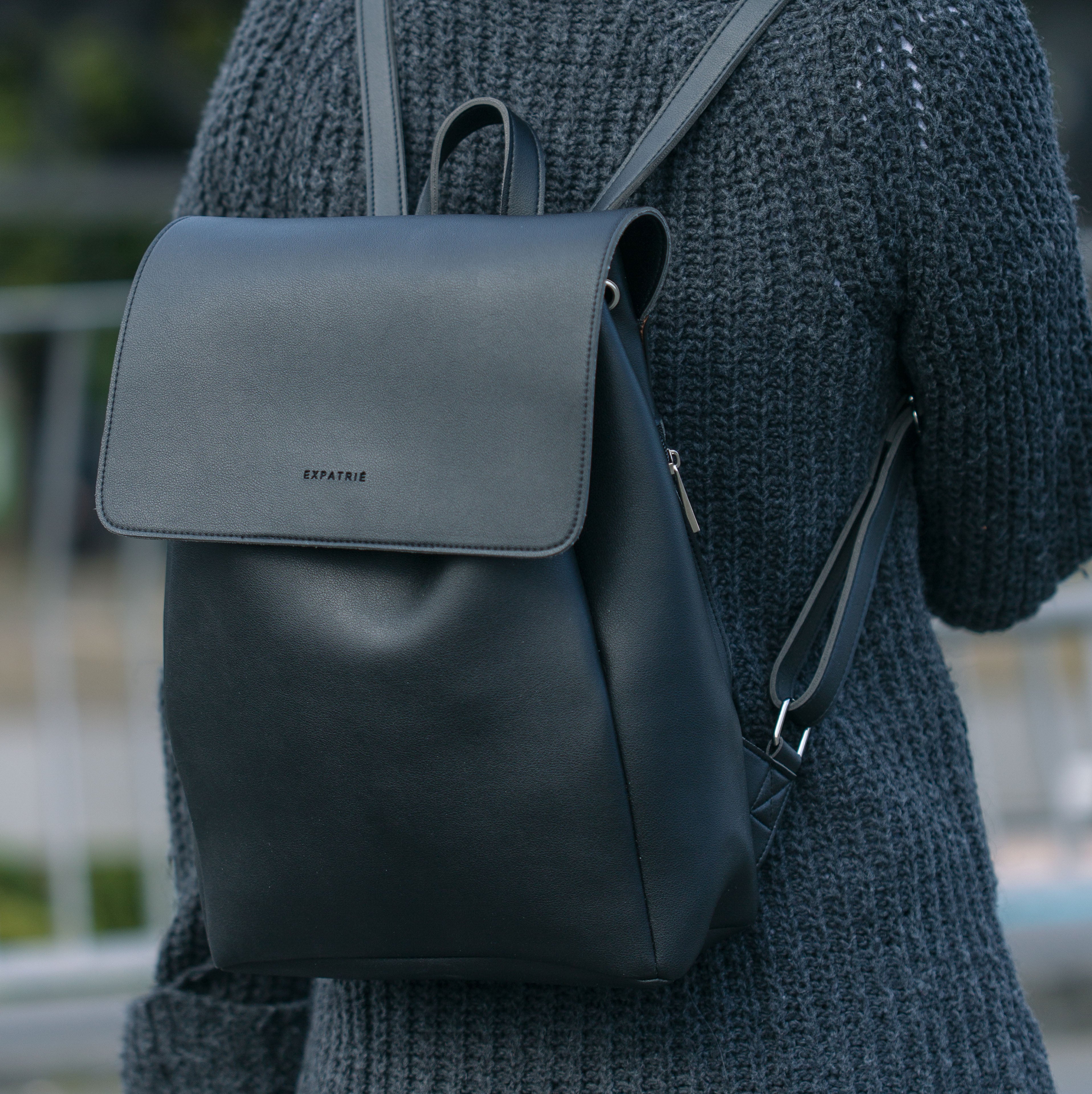 Schwarzer Kunstleder-Rucksack Noelle von Expatrié an Frau mit grauem Strickpullover