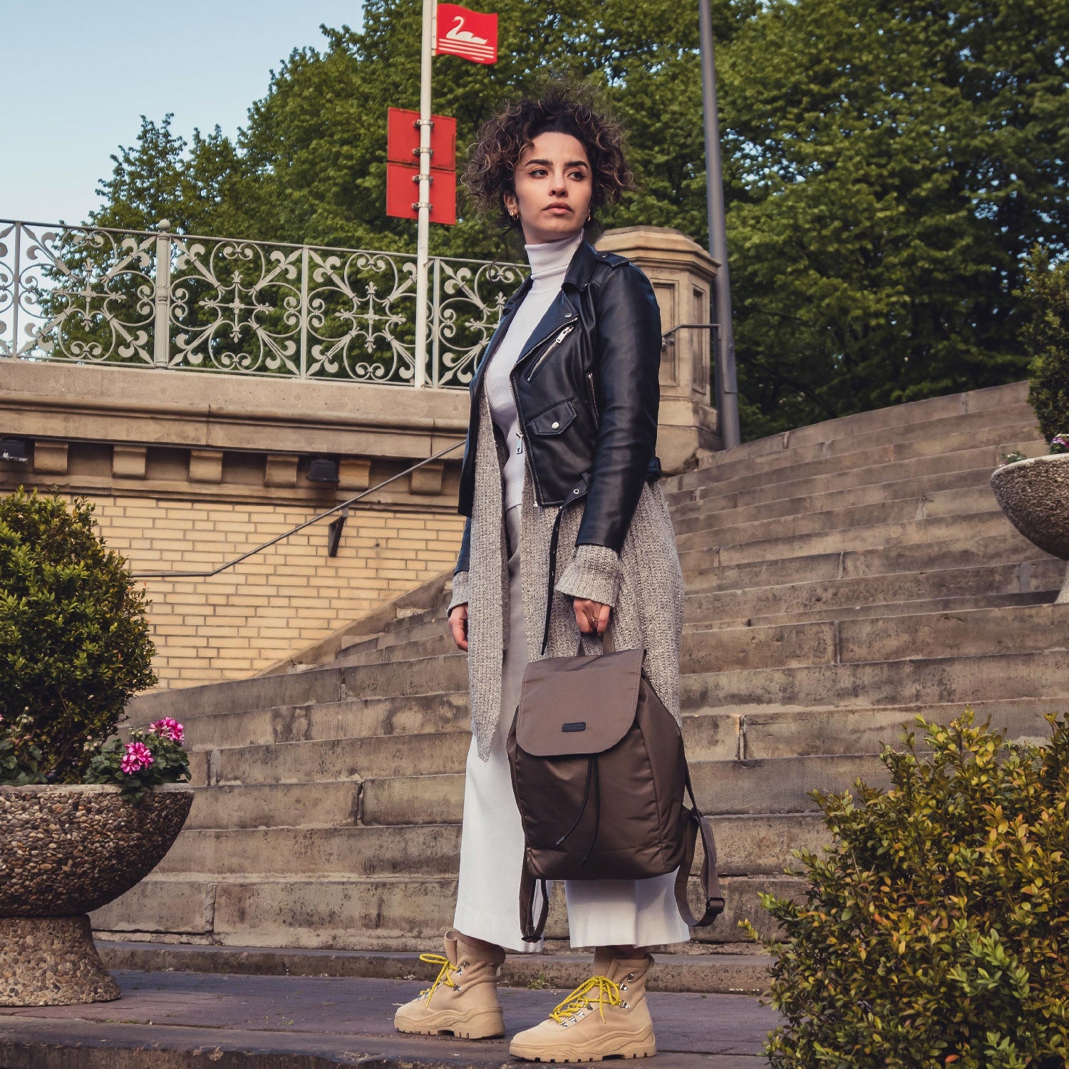 Frau steht auf einer Treppe, trägt einen hellbraunen Nylon Rucksack Clara und modische Kleidung