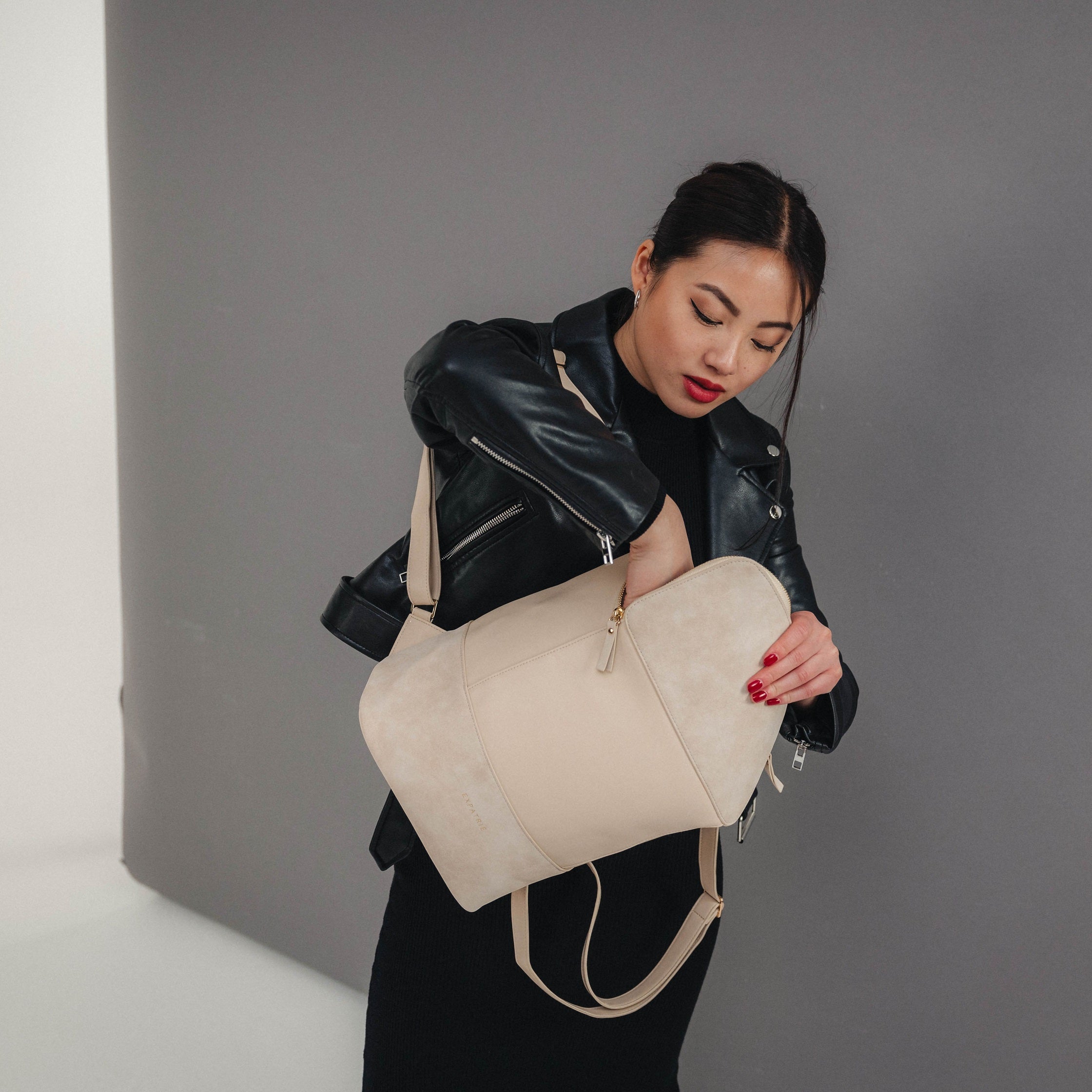 Dame mit schwarzer Lederjacke hält eleganten beige Rucksack Malou mit Reißverschluss