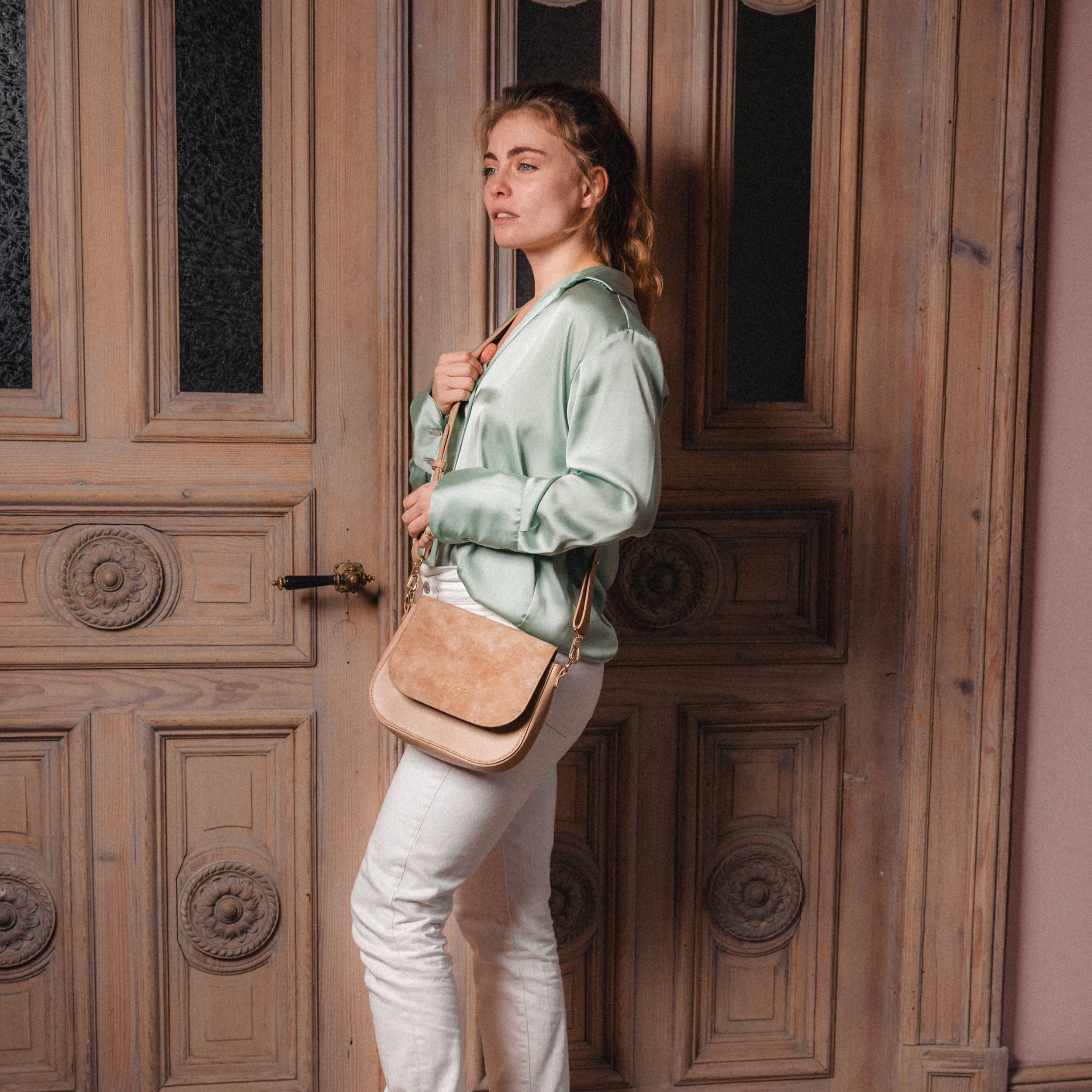 Frau trägt beige Saddle Bag Louise Medium aus Wildleder mit verstellbarem Schulterriemen