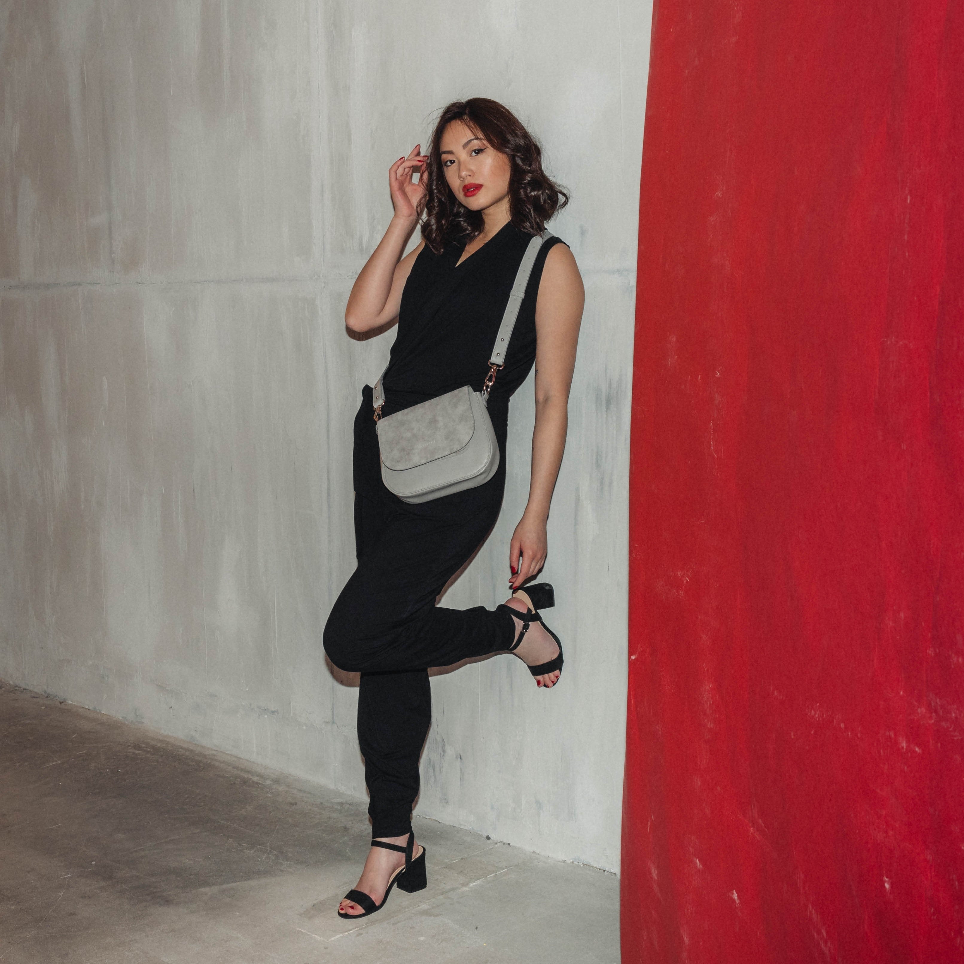 Frau in schwarzem Jumpsuit trägt graue Saddle Bag Louise Medium Umhängetasche
