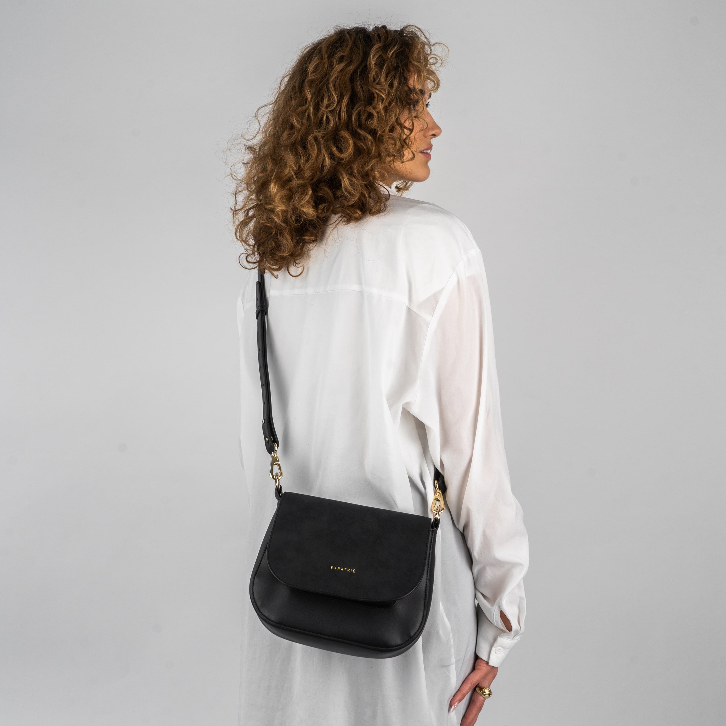 Schwarze Saddle Bag Louise Medium aus Leder an Frau mit weißen Hemd von hinten getragen