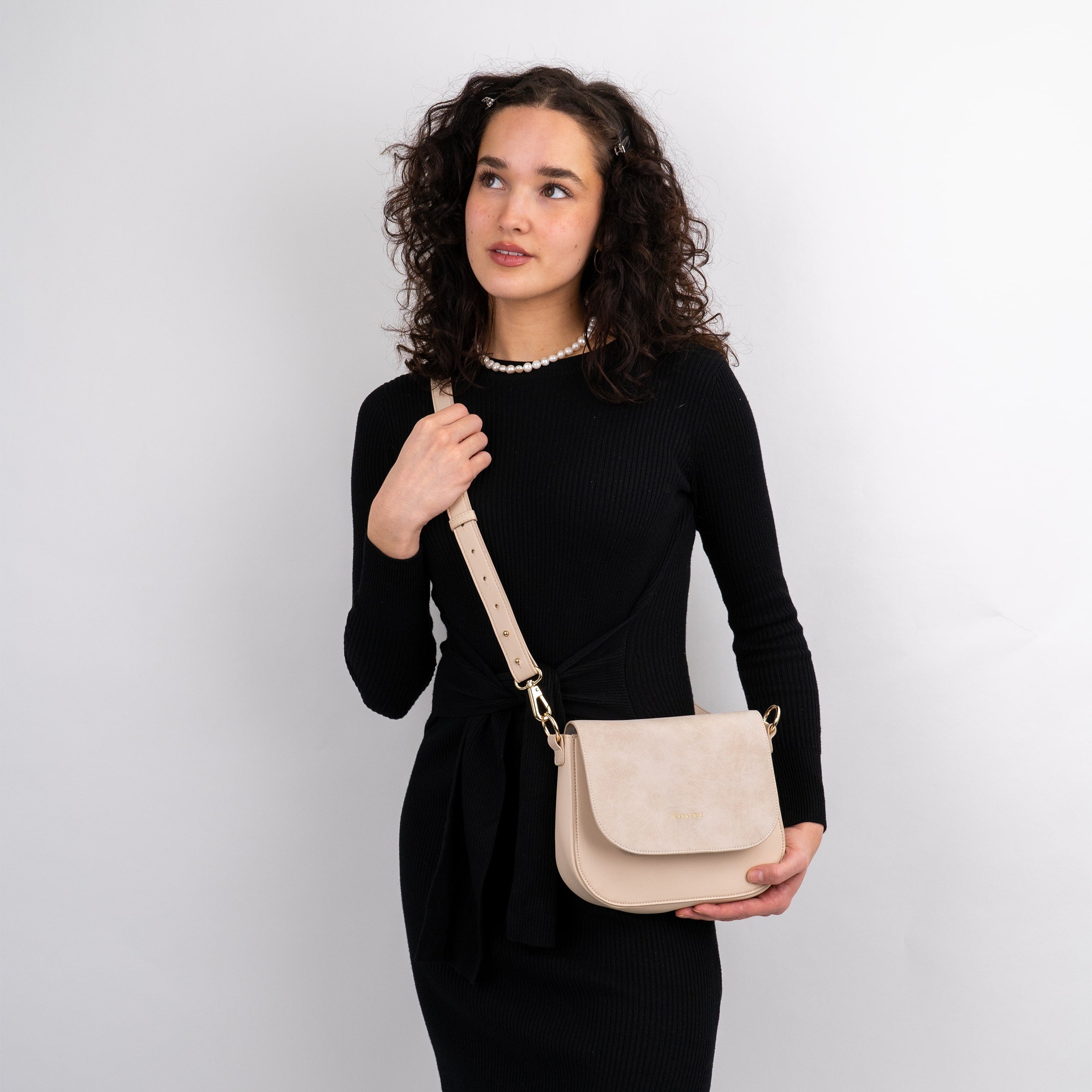 Frau trägt beige Saddle Bag Louise Medium Umhängetasche aus weichem Material