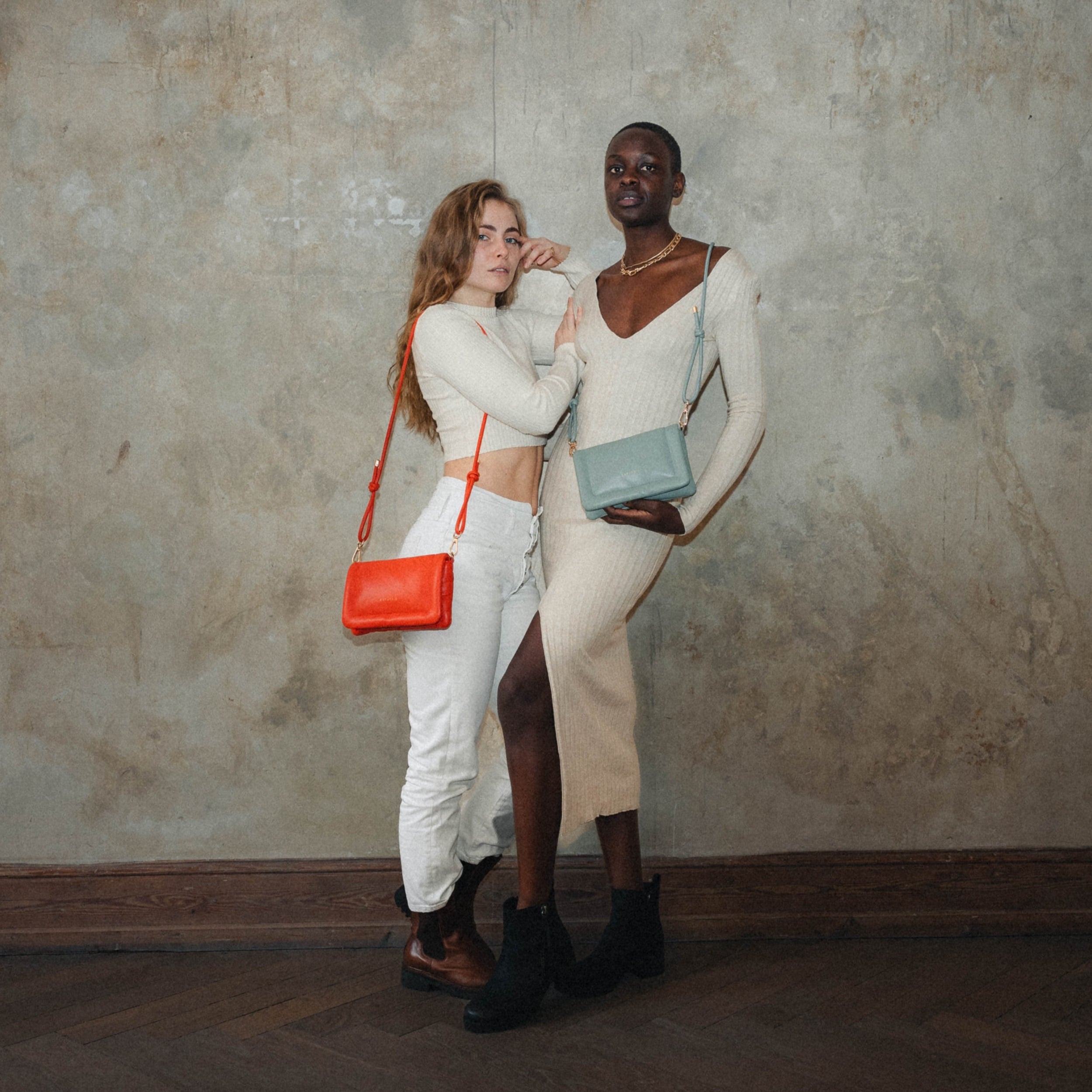 Zwei Frauen mit Umhängetaschen Zoe Small in Orange und Hellblau vor grauer Wand