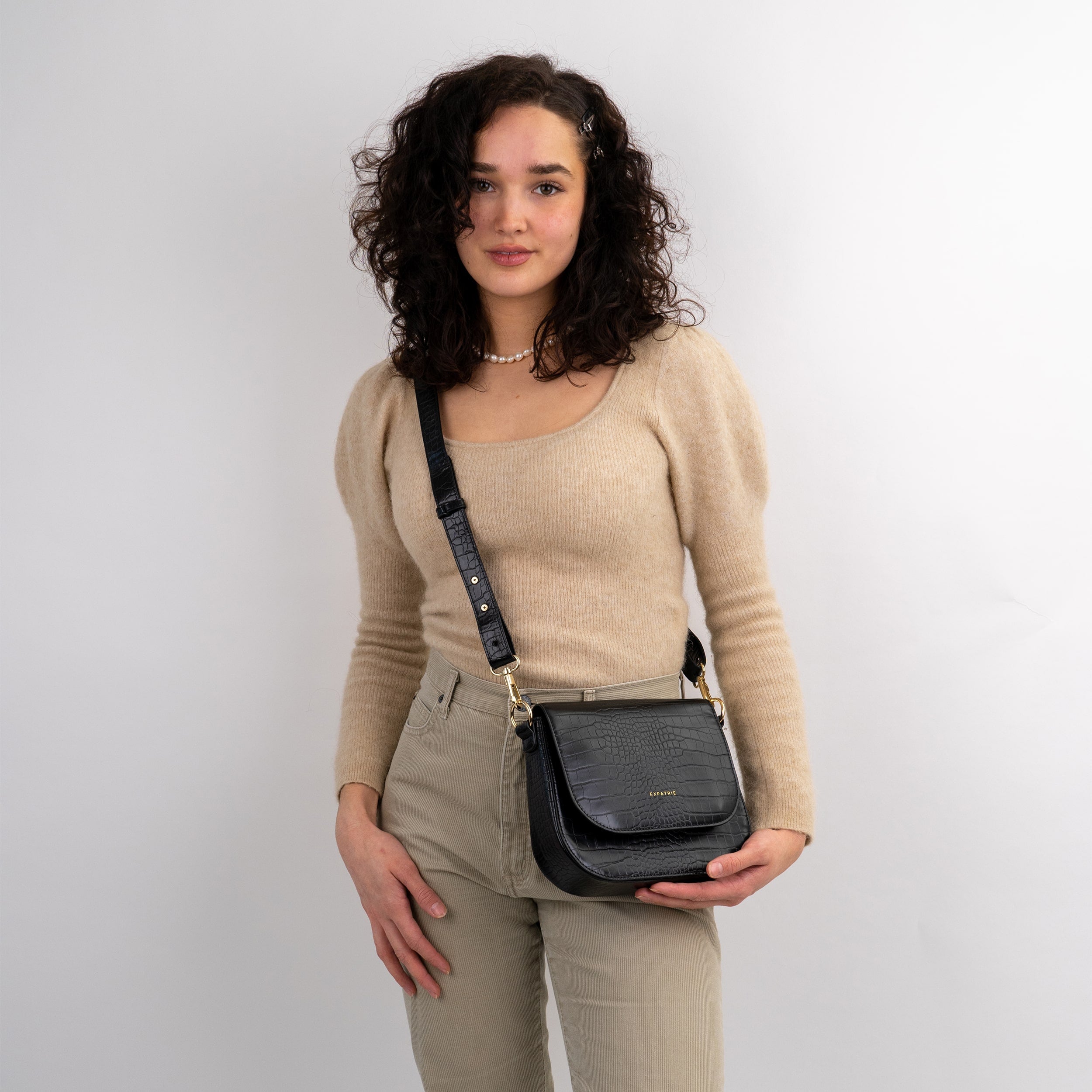Frau trägt schwarze Umhängetasche Saddle Bag Louise Medium mit Krokodilprägung