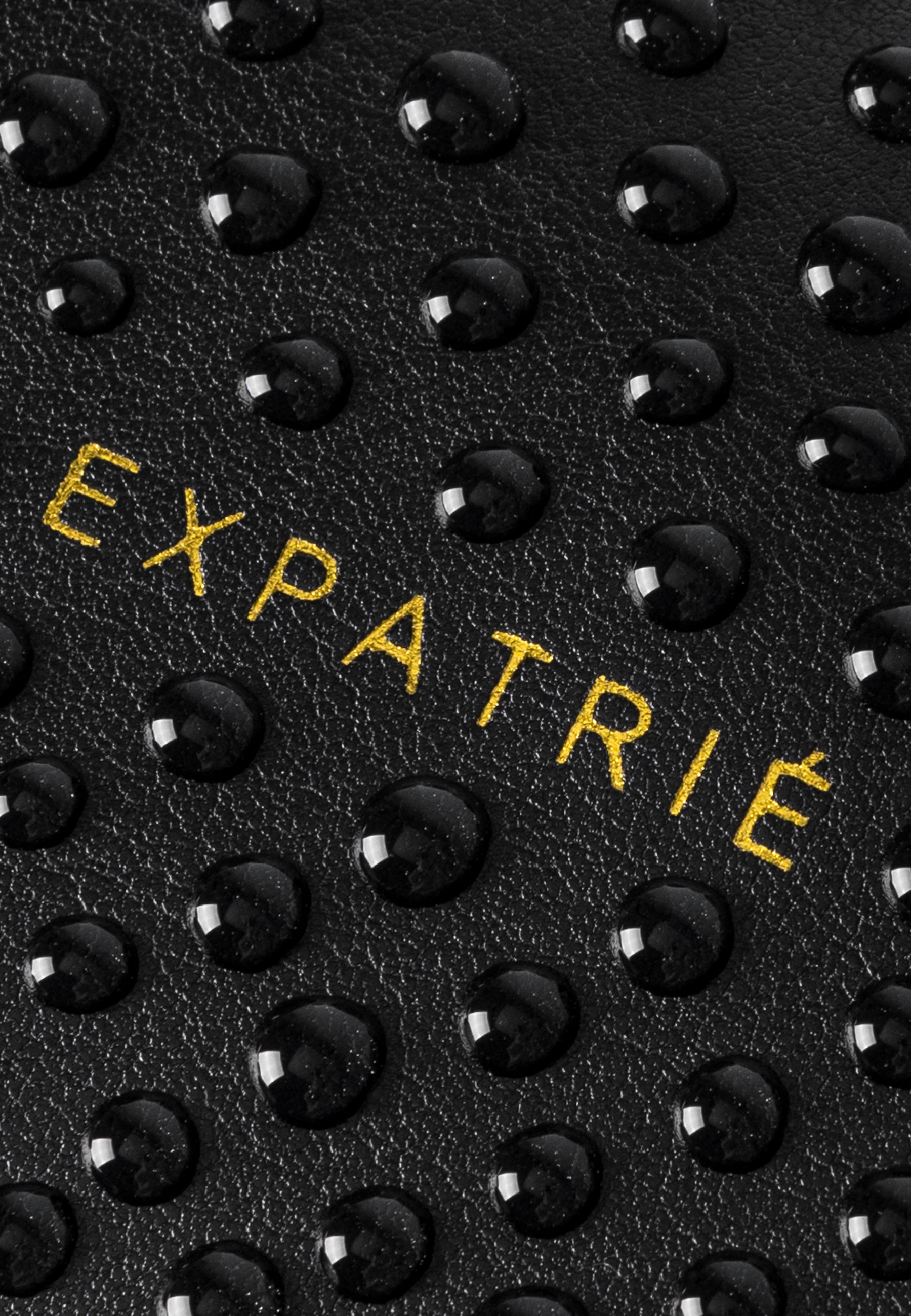 Wasserabweisende schwarze Oberfläche mit gelbem 'EXPATRIÉ' Schriftzug auf LEA SMALL Half Moon Bag