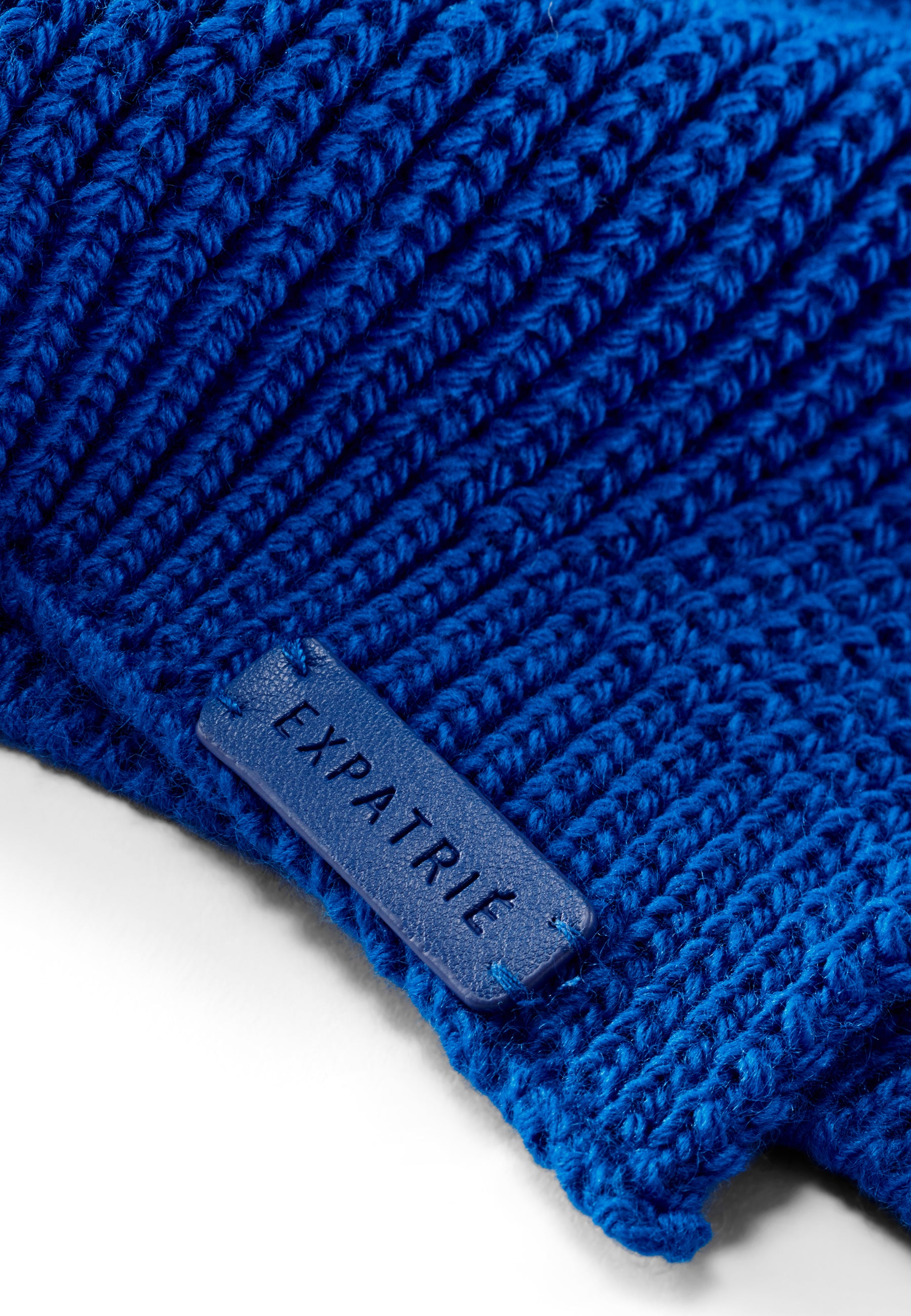 Nahaufnahme eines royalblauen, gestrickten Damen-Schals mit labelaufnäher 'Expatrié'