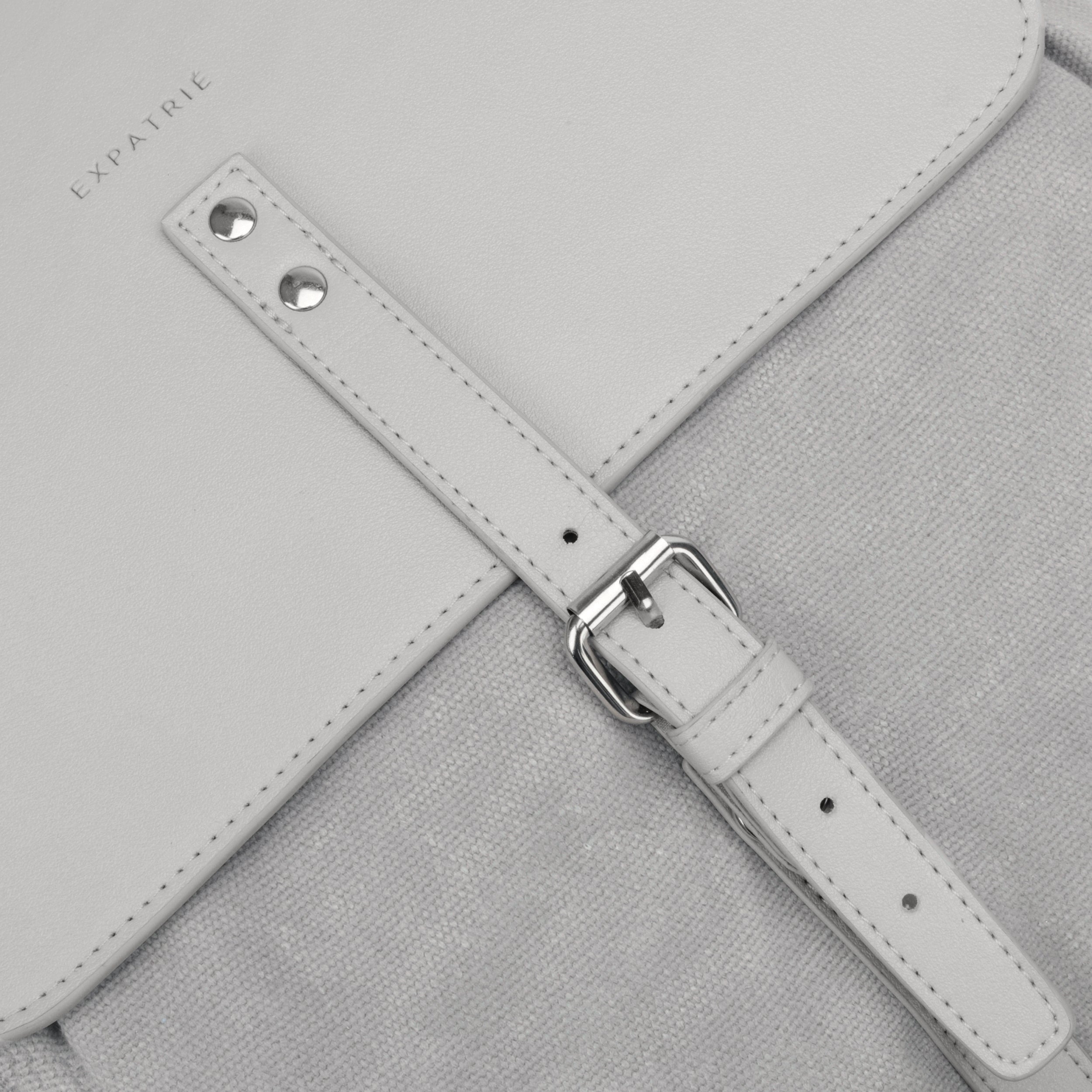 Detailaufnahme des grauen Canvas-Rucksacks Laurent von Expatrié mit Lederriemen und Metallverschluss